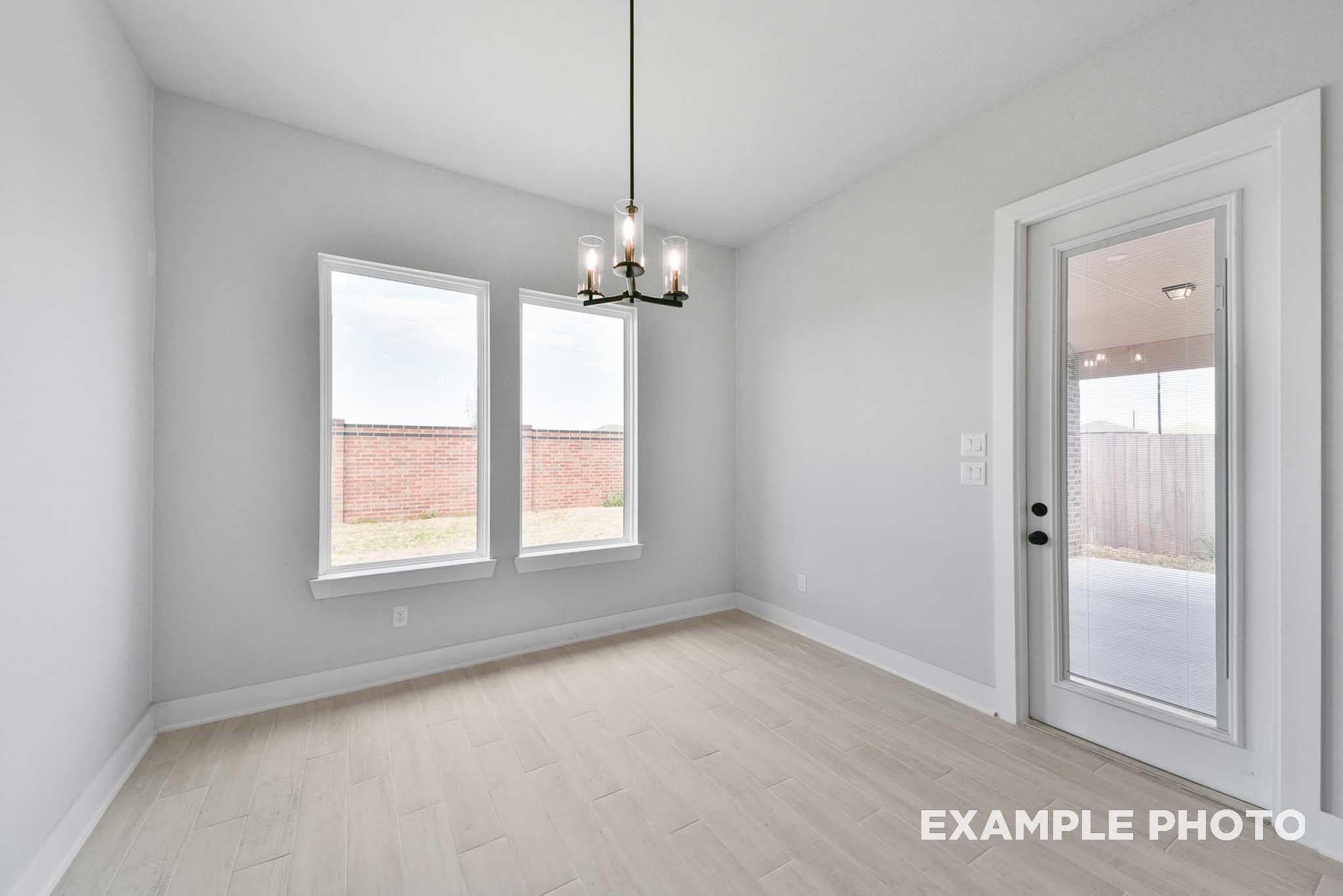 Bright empty study with light gray walls, chandelier, large windows, glass patio door in Davidson Homes The George A, Lago Mar
