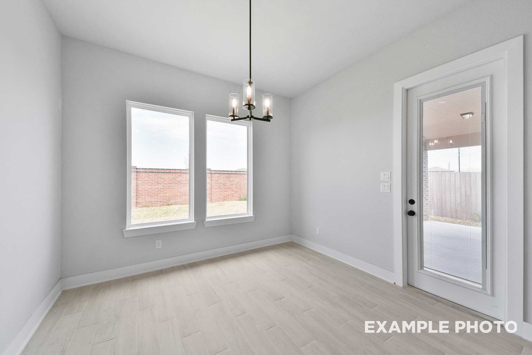 Bright empty study with light gray walls, chandelier, large windows, glass patio door in Davidson Homes The George A, Lago Mar
