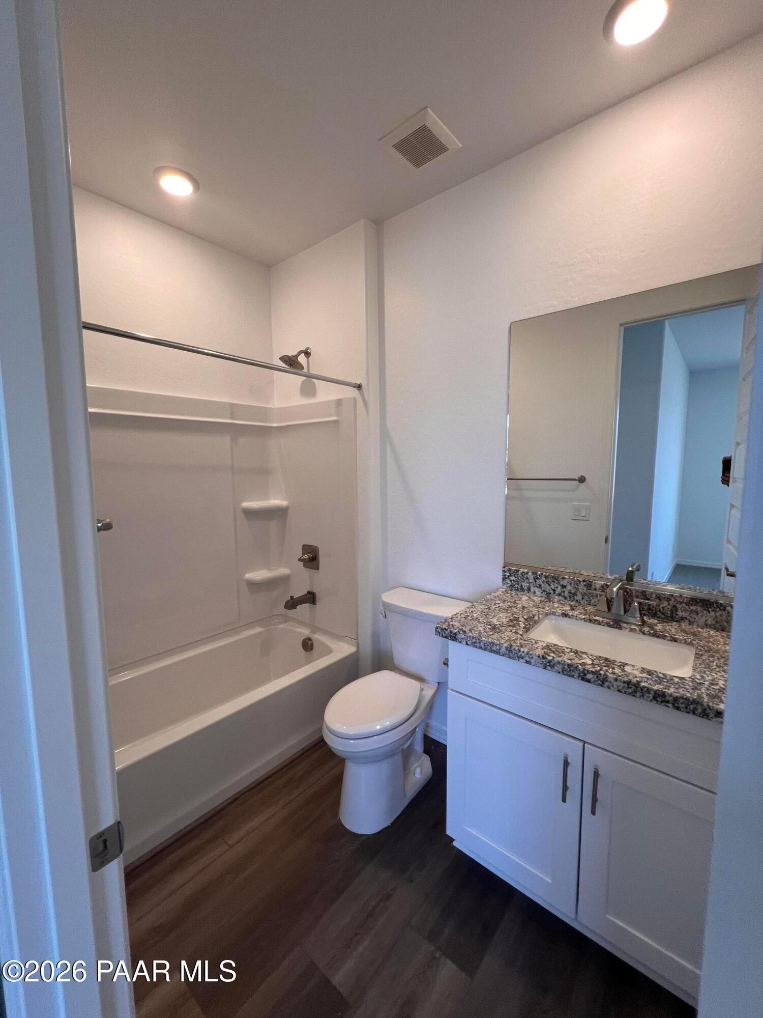 Modern bathroom with deep tub, granite countertop vanity, white cabinets, and luxury vinyl plank flooring in Davidson Homes The Summit A, Prescott, Arizona