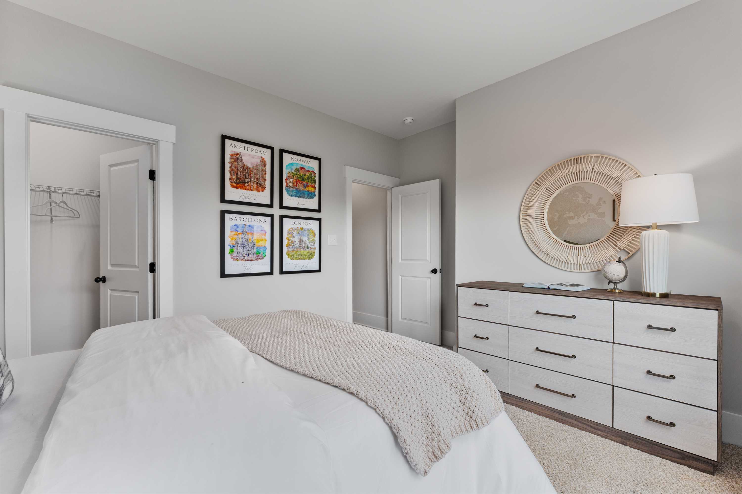 Cozy bedroom interior at River Road Estates in Decatur, Alabama with white king bed, dresser, and framed artwork