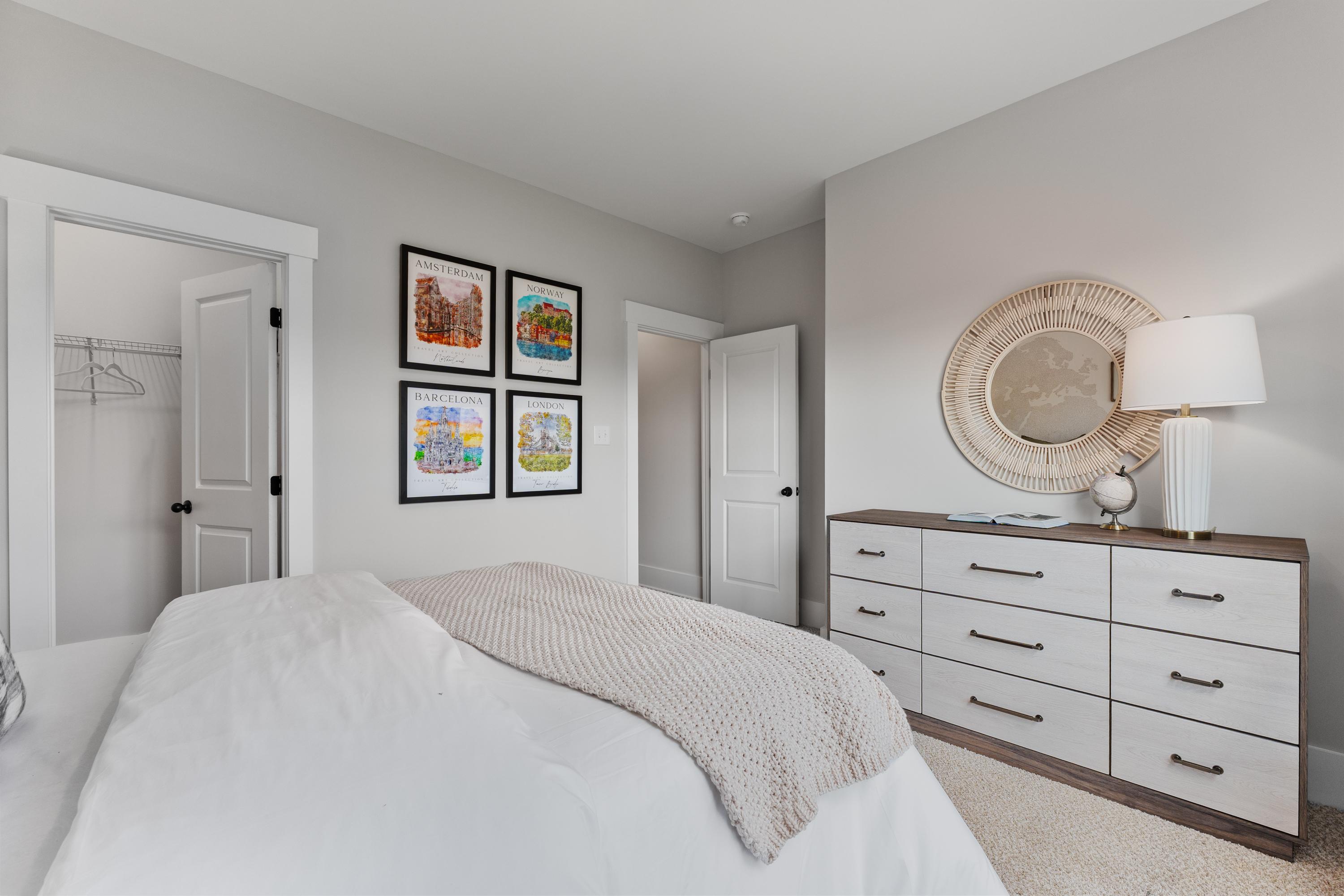 Cozy bedroom interior at River Road Estates in Decatur, Alabama with white king bed, dresser, and framed artwork