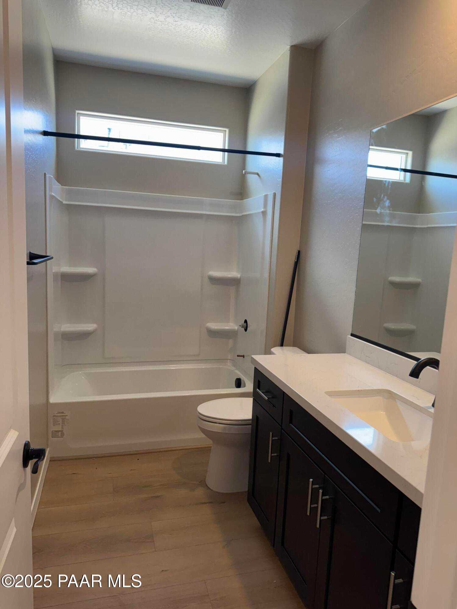 Bright bathroom with white tub, dark wood vanity, large mirror, and window in Davidson Homes The Sheridan II B, Prescott, Arizona