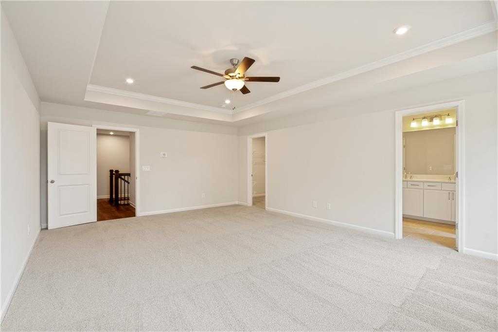 Spacious upstairs loft with ceiling fan, beige carpet, and adjacent bathroom in Davidson Homes Cary B, Kennesaw, GA