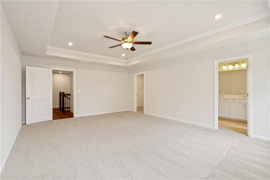 Spacious upstairs loft with ceiling fan, beige carpet, and adjacent bathroom in Davidson Homes Cary B, Kennesaw, GA