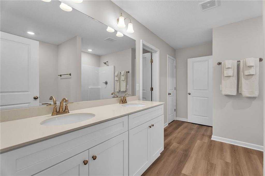 Elegant double vanity master bathroom with white cabinets, gold faucets, large mirror in Davidson Homes The Bartlett, Phenix City, Alabama