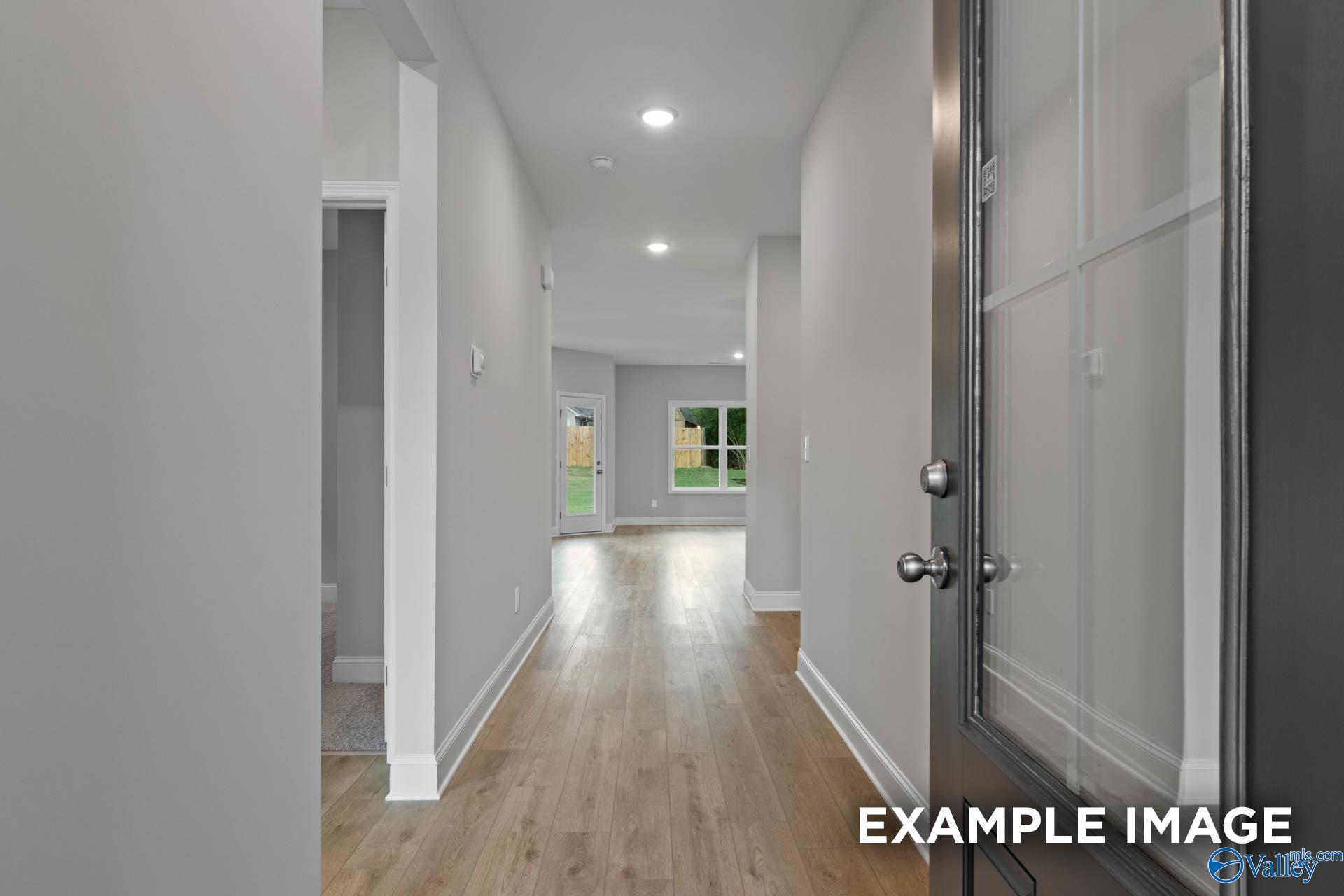 Bright entry hallway with hardwood floors, gray walls, and glass front door in Davidson Homes The Franklin C, Toney Alabama