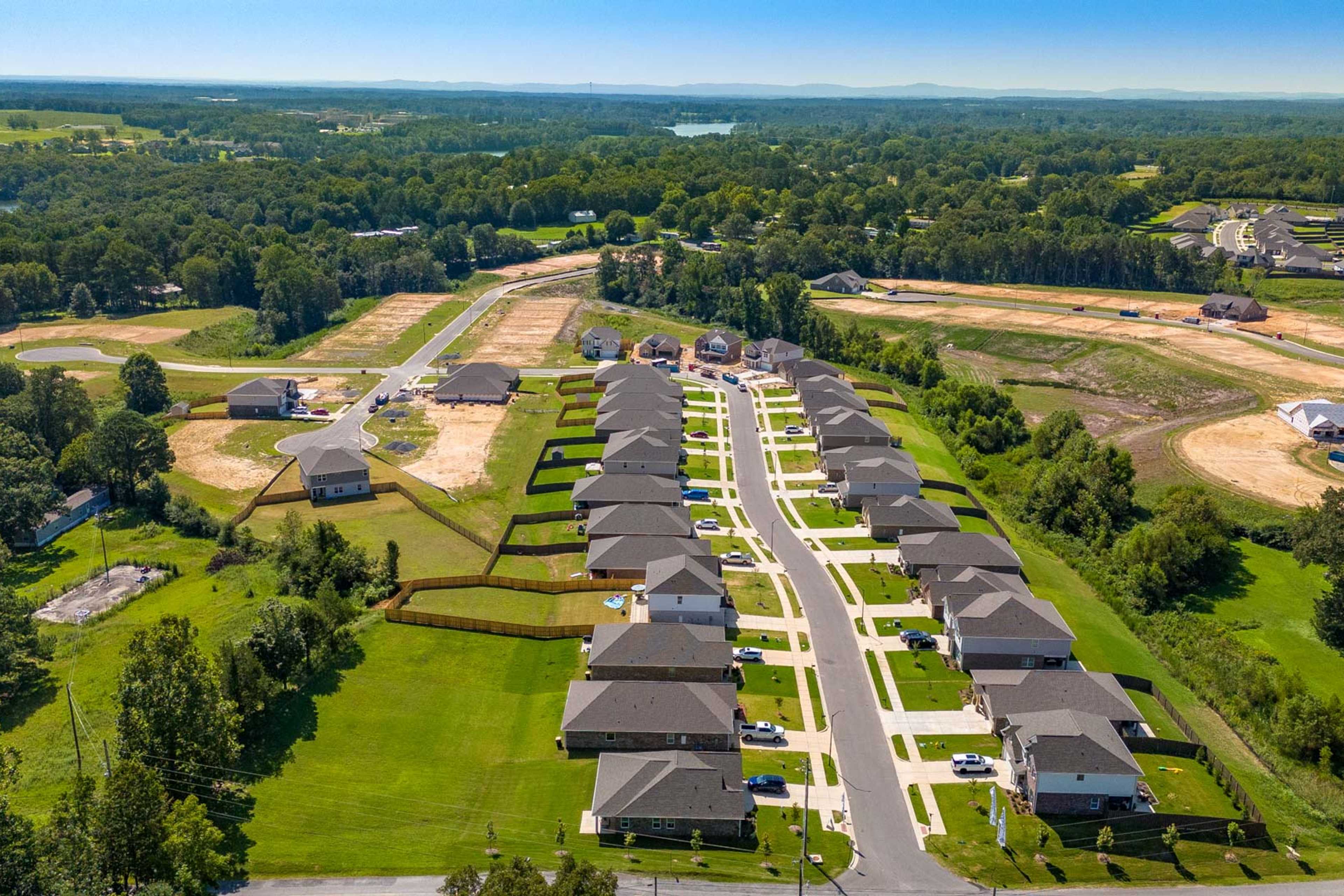 Aerial view of new homes along tree-lined streets in The Reserve at North Ridge, Cullman Alabama with surrounding woods and construction