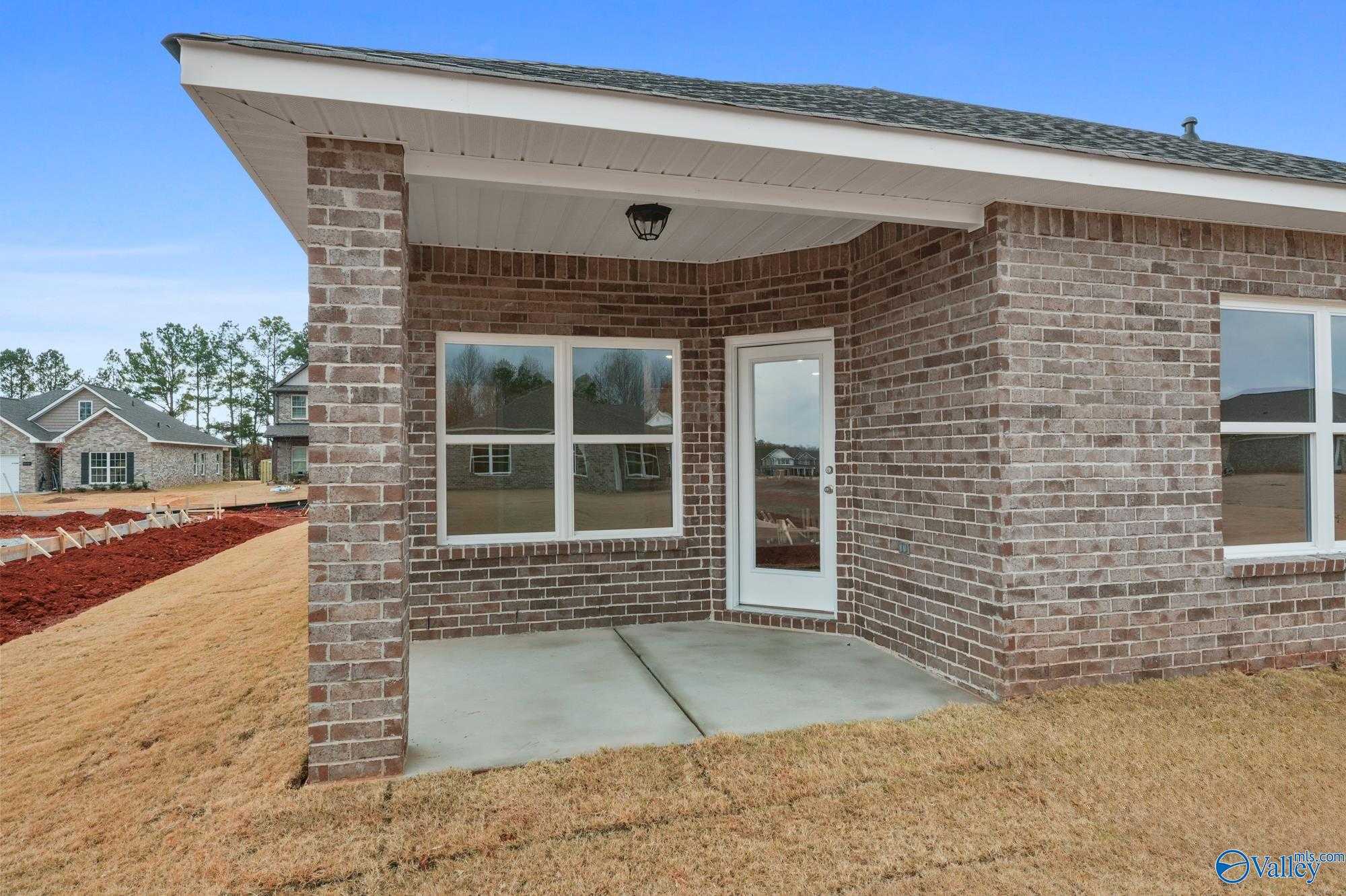 Brick single-story home exterior with covered front porch, large windows, and brick facade in Ricketts Farm, Athens, Alabama