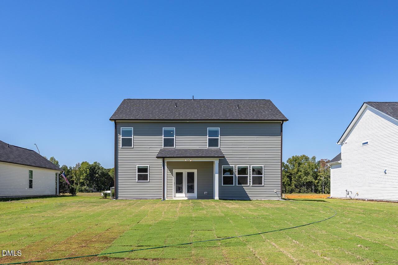 Two-story gray siding home with covered rear porch and spacious backyard in Retreat at North Main, Lillington, North Carolina