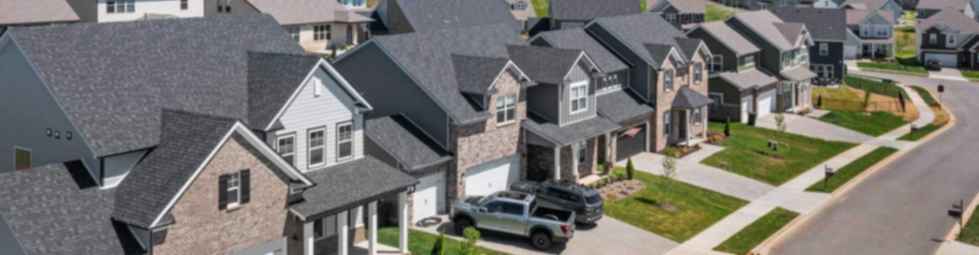 Aerial view of modern new construction homes lining streets in Hendersonville community, with driveways, lawns, and lush hills