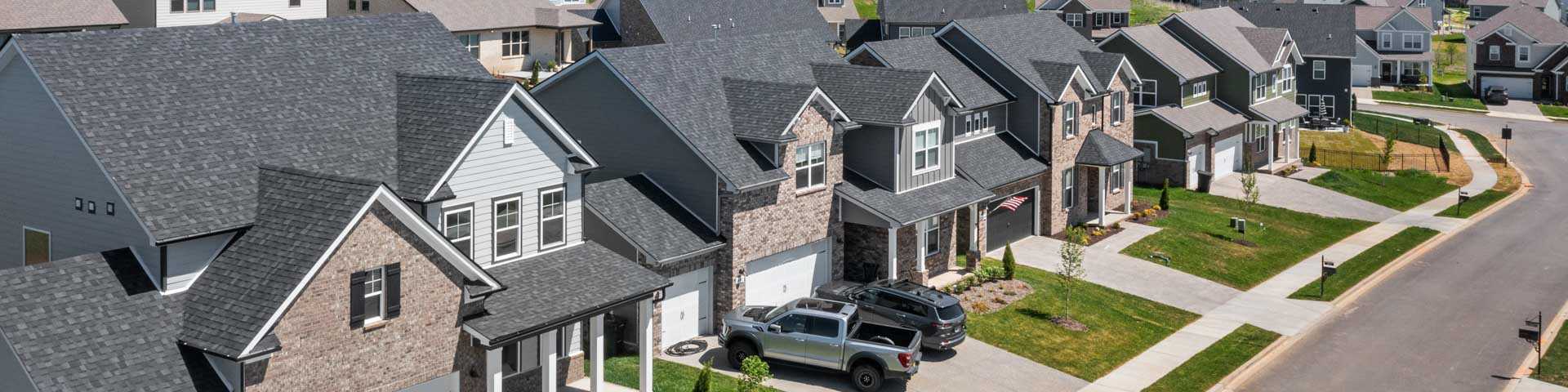 Aerial view of modern new construction homes lining streets in Hendersonville community, with driveways, lawns, and lush hills