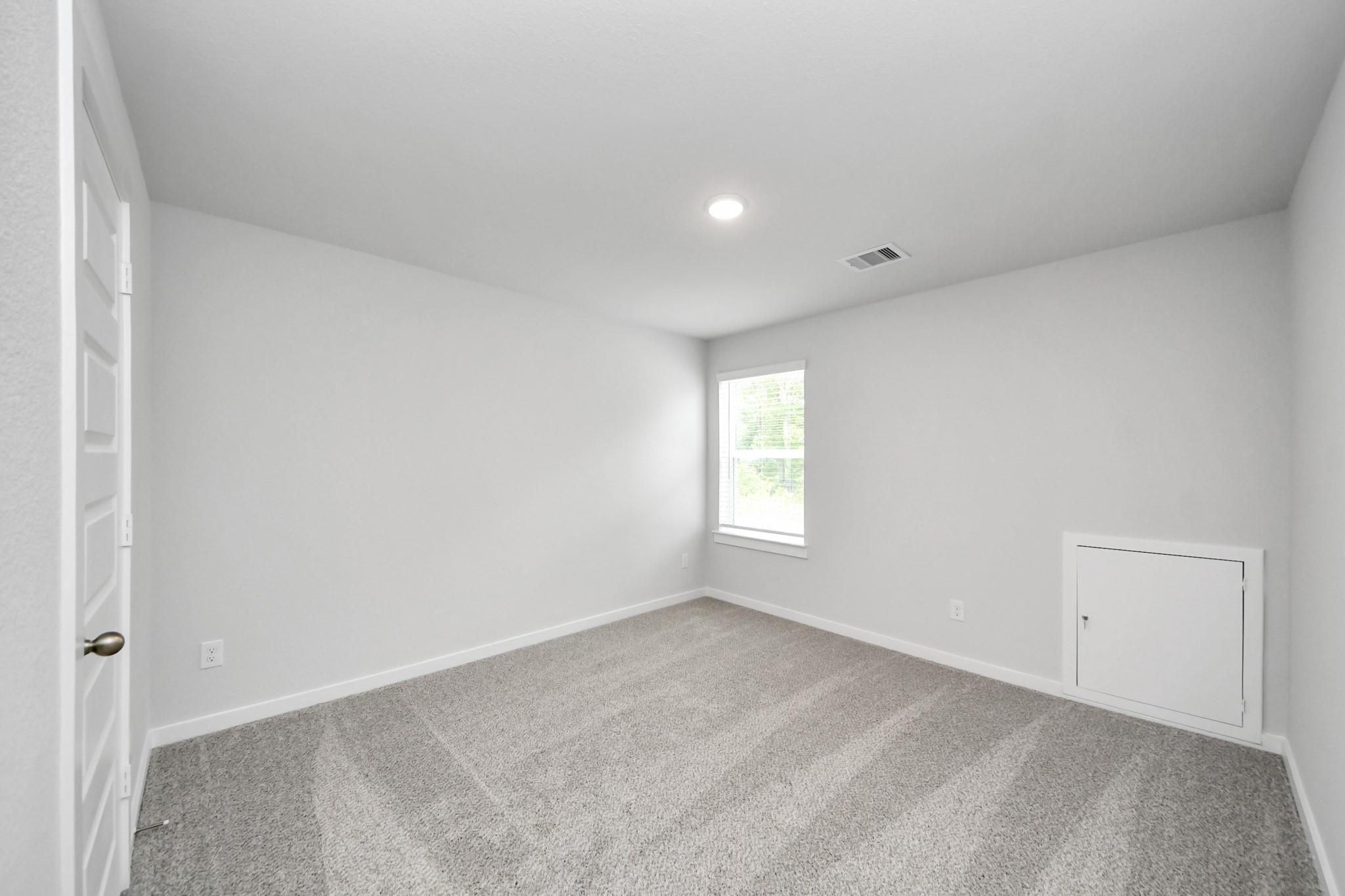 Bright, neutral-toned bedroom with plush carpeting in The Sabine E floor plan at Liberty Estates, Cleveland, Texas.