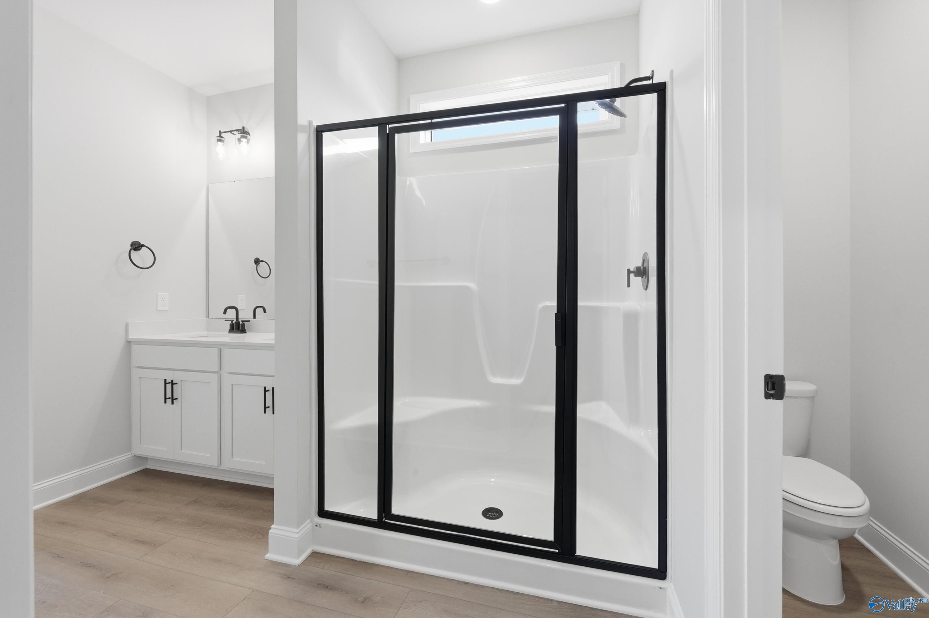 Modern master bathroom with frameless glass shower, white tile, vanity sink and toilet in Davidson Homes The Daphne D, Arab, AL