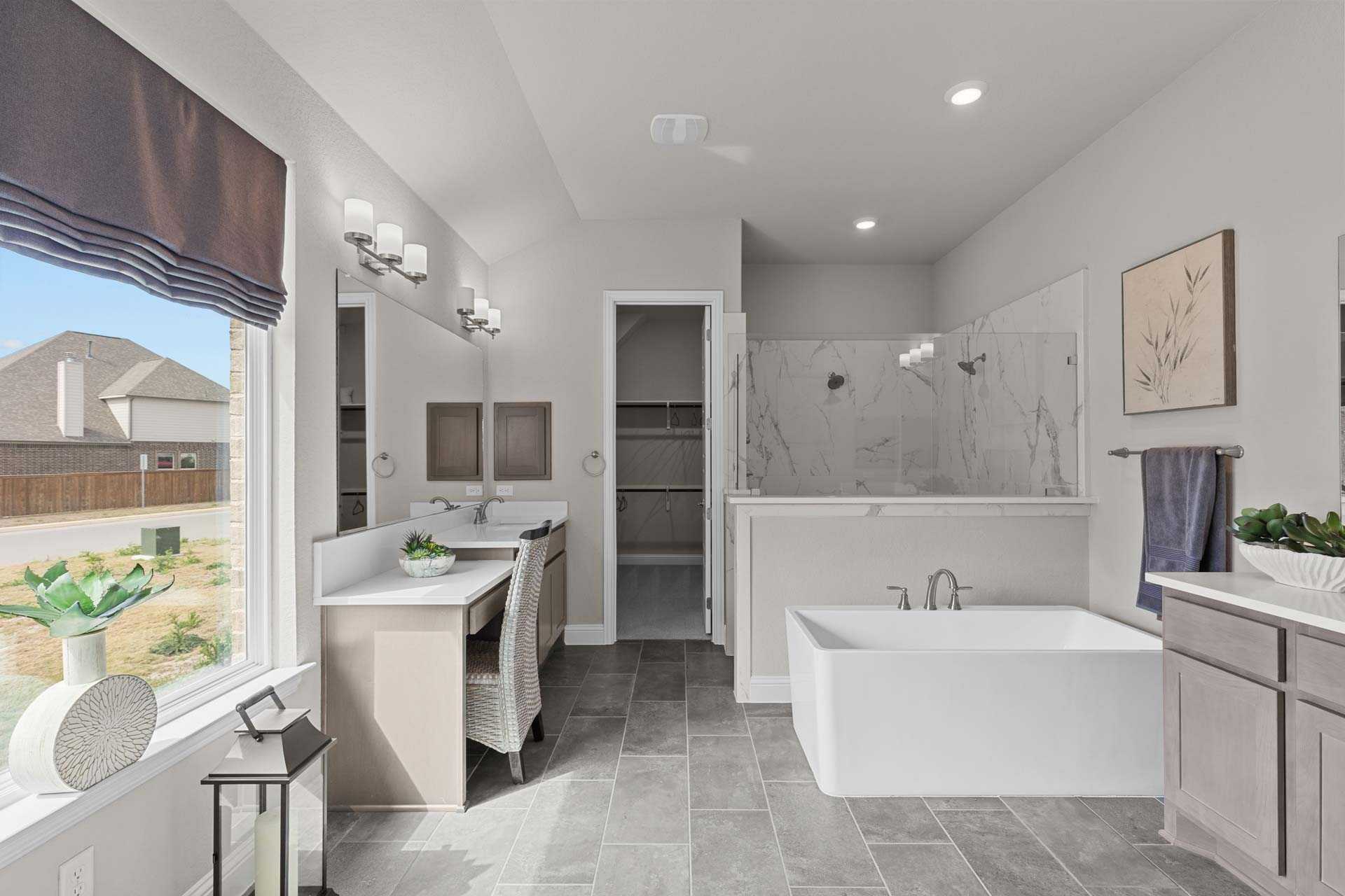 Spacious master bathroom in The Garner A with freestanding tub, walk-in glass shower, dual vanities, and large window
