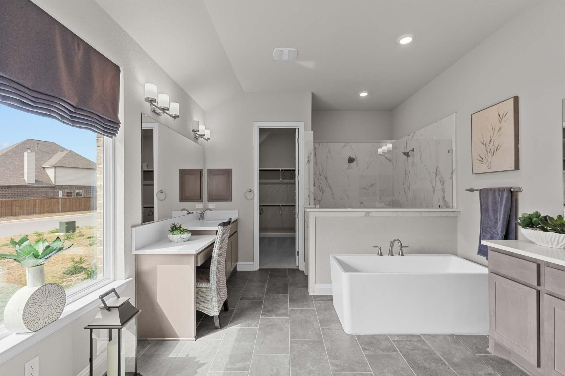 Spacious master bathroom in The Garner A with freestanding tub, walk-in glass shower, dual vanities, and large window