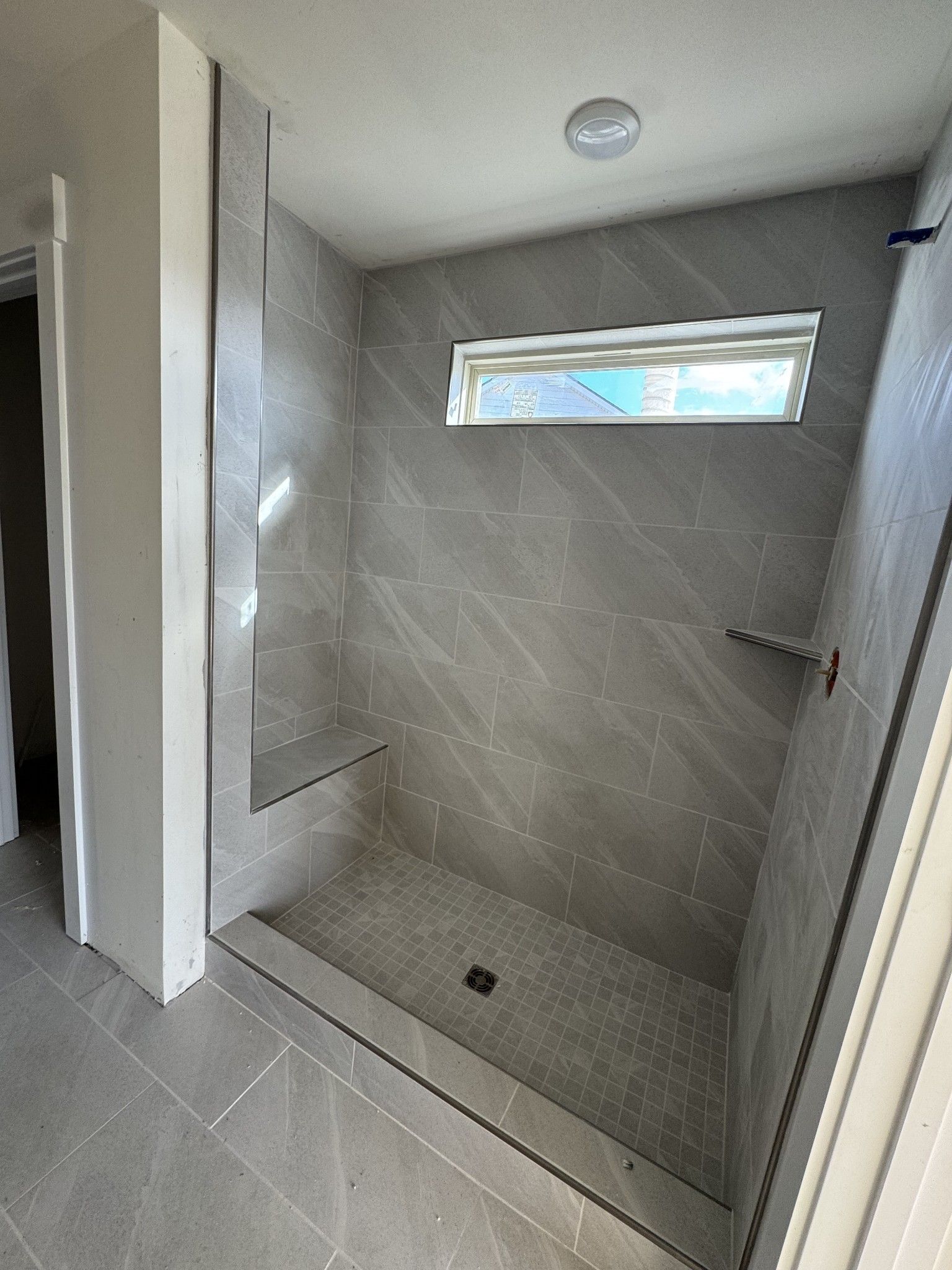 Modern walk-in shower with gray subway tiles, built-in bench, and frosted window in Davidson Homes The Willow C, Gallatin, TN