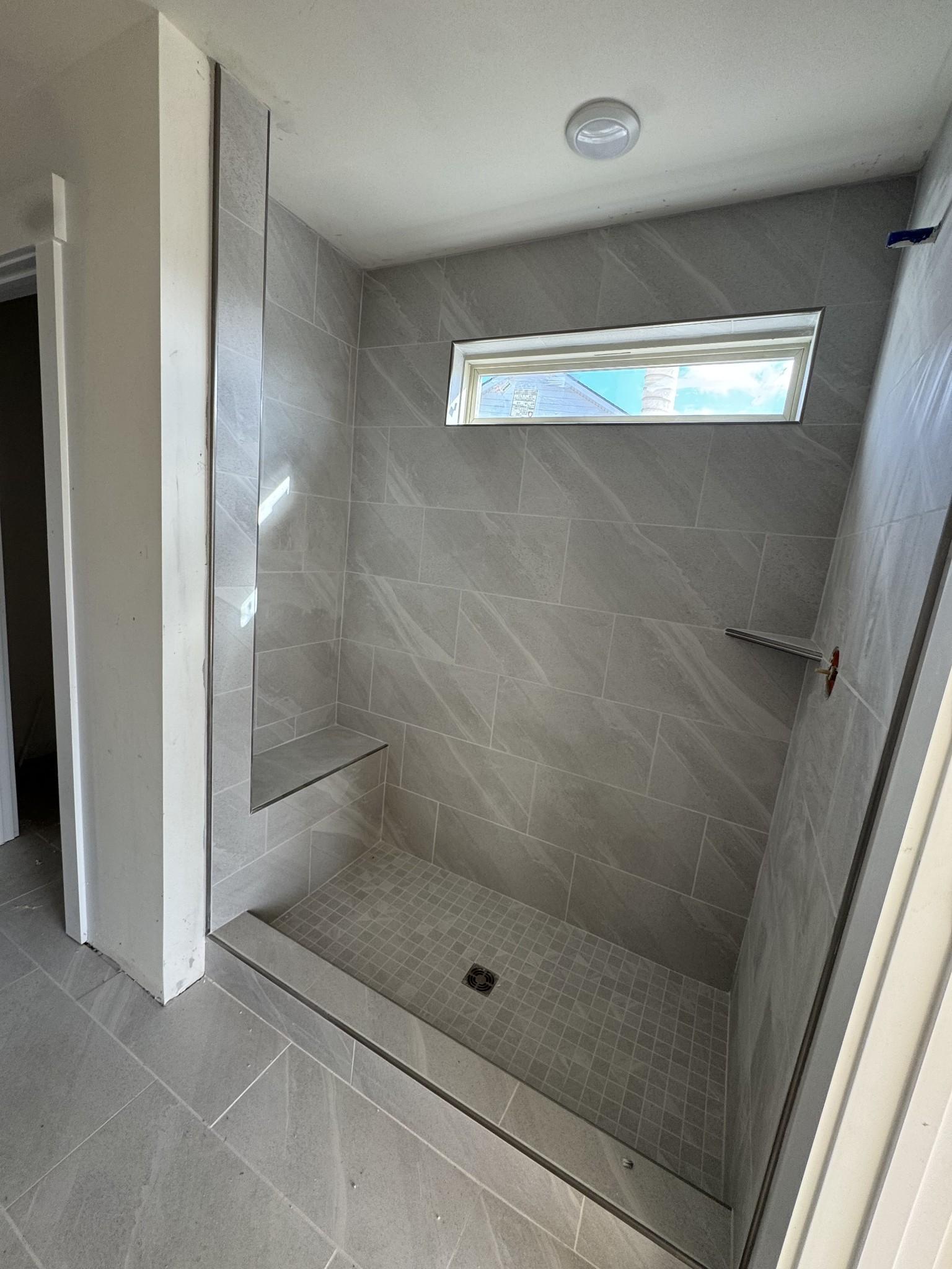 Modern walk-in shower with gray subway tiles, built-in bench, and frosted window in Davidson Homes The Willow C master bath, Gallatin, TN