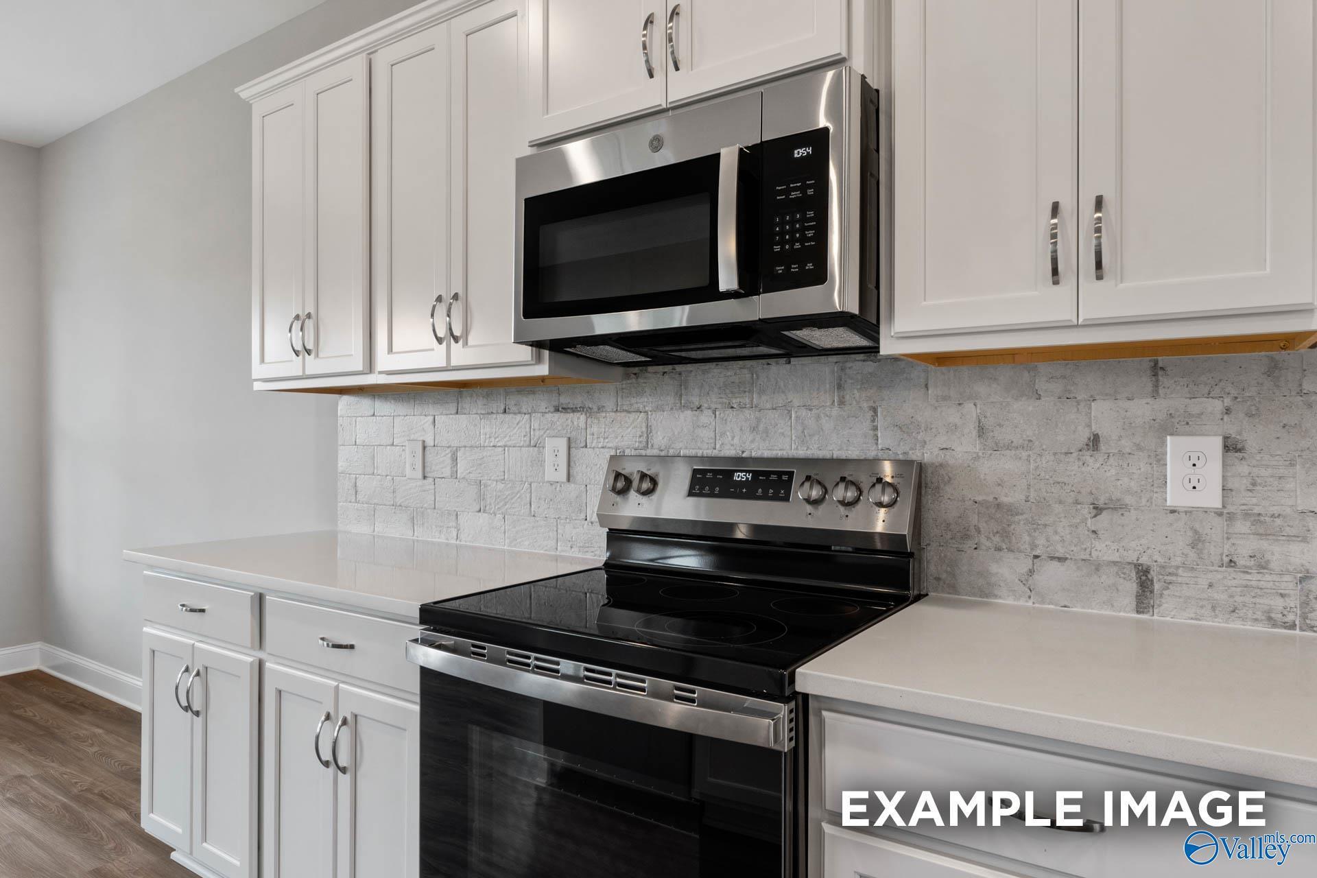 Modern kitchen featuring white shaker cabinets, stainless steel range and microwave, subway tile backsplash in Davidson Homes The Shelby B, Athens AL