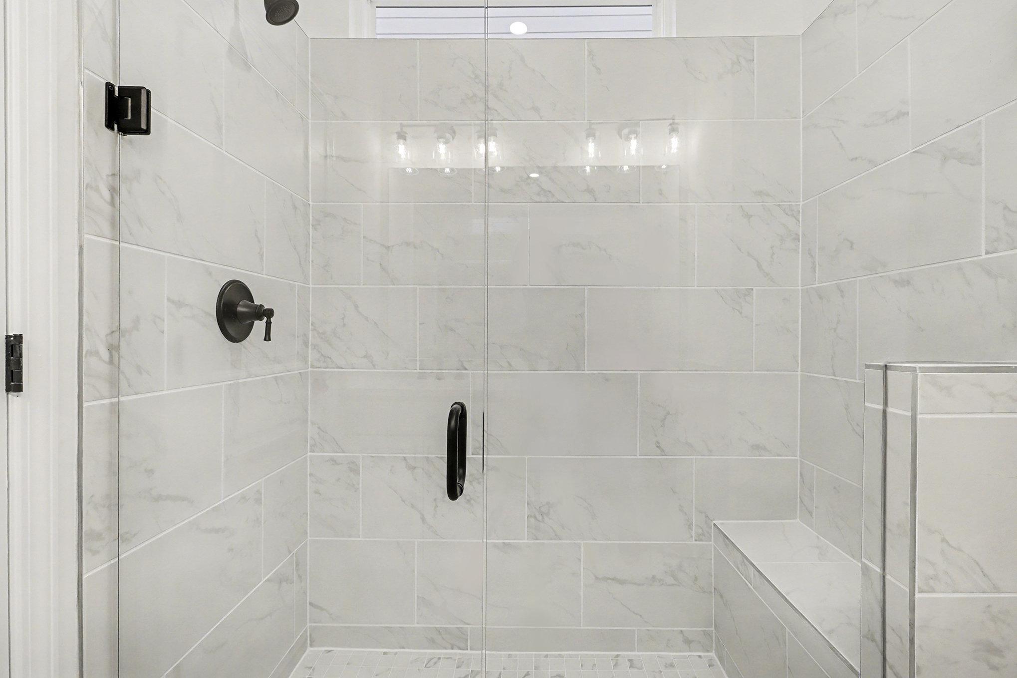 Modern master bathroom with frameless glass shower, white subway tile, and adjacent bedroom in Davidson Homes The Daphne B, Loganville, GA