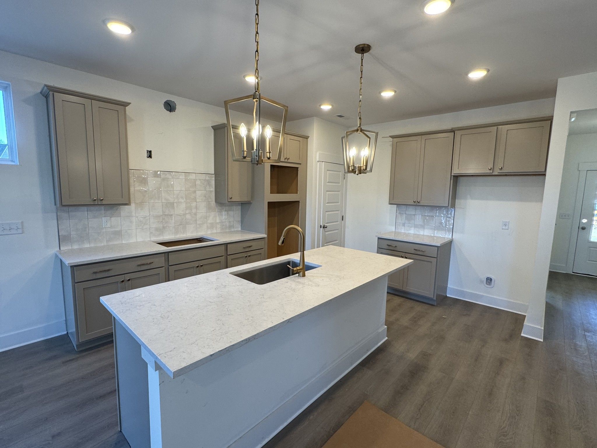 Modern kitchen with white quartz island, subway tile backsplash, shaker cabinets, and pendant lights in The Ash A floor plan, Gallatin, TN
