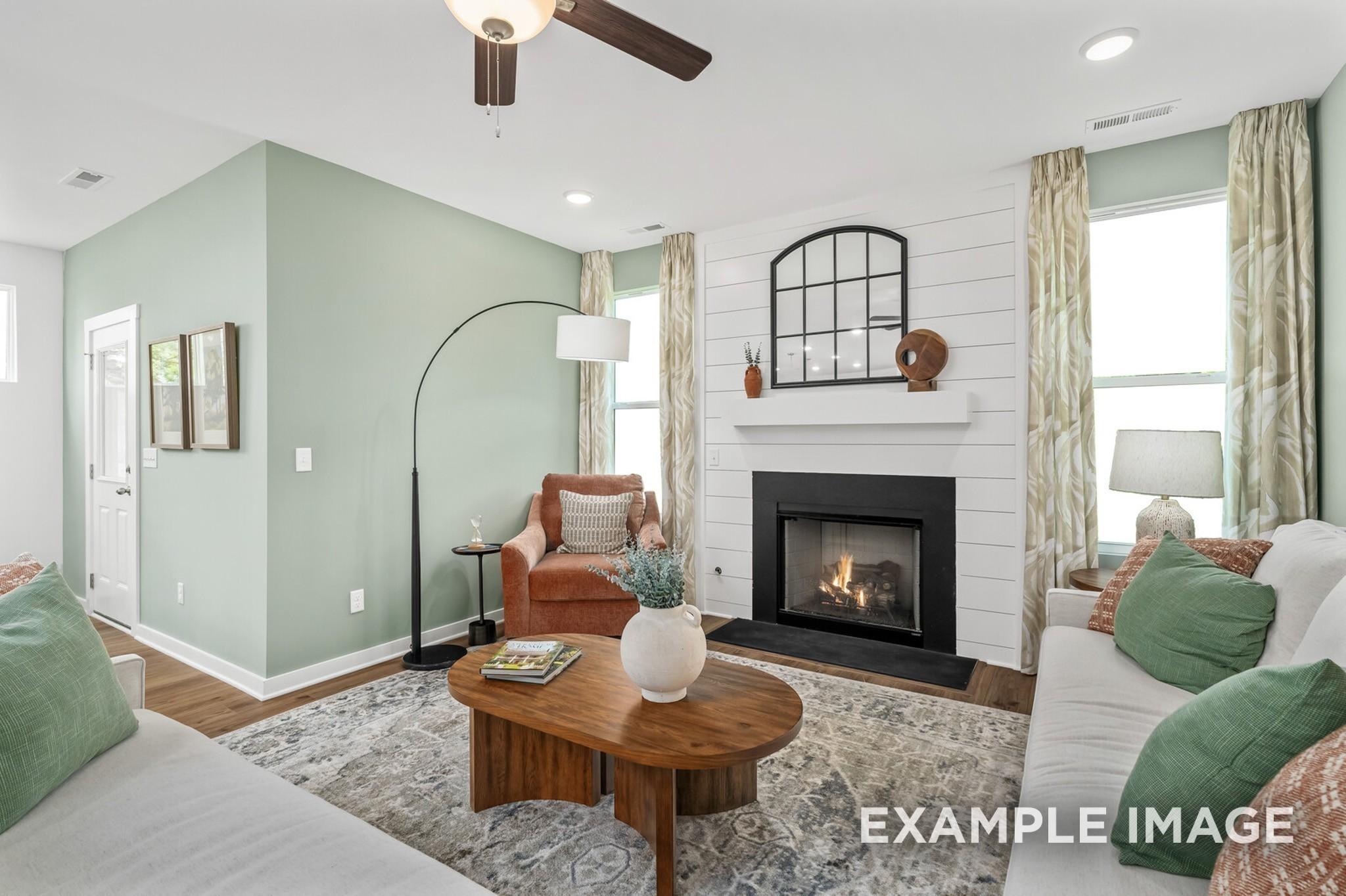 Cozy living room with shiplap fireplace and sage green walls in The Ash A floor plan at Woods Crossing, Gallatin, TN.