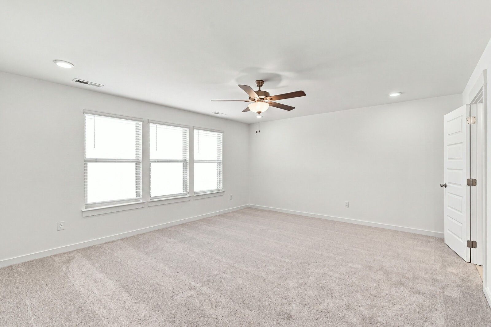 Spacious carpeted bedroom with ceiling fan and three windows in Davidson Homes The Willow C, Gallatin, Tennessee