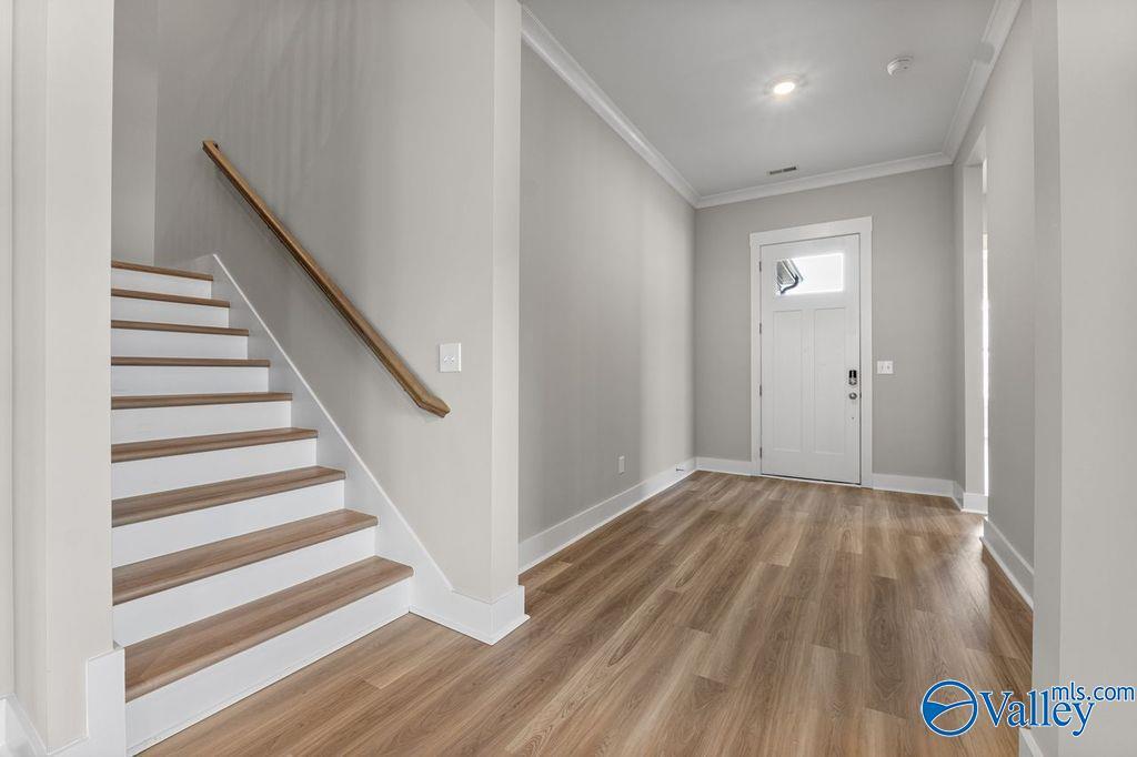 Elegant oak staircase with white risers in light gray foyer of Evermore Homes The Oxford, Owens Cross Roads, Alabama