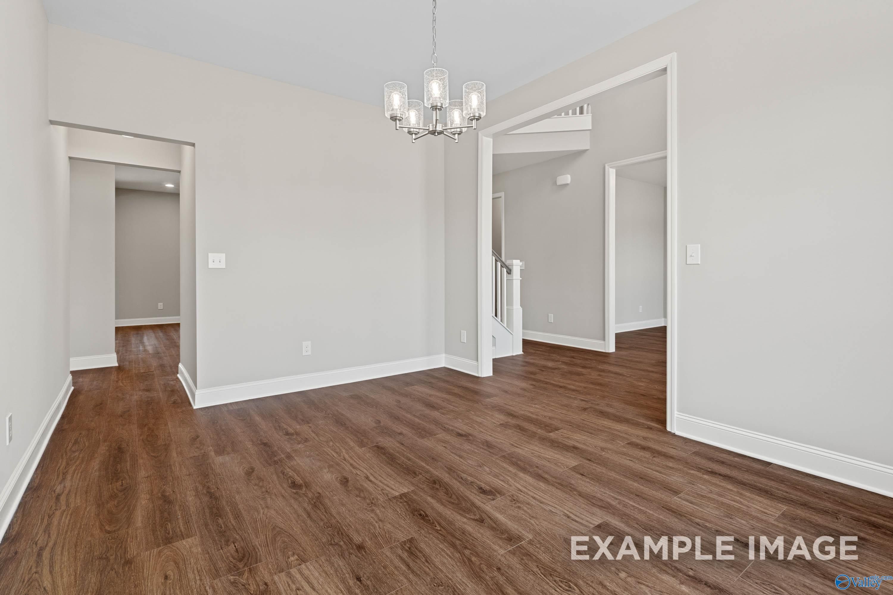 Bright dining room with modern chandelier and wood-look flooring in The Madison D floor plan at Evergreen Mill, Madison AL.