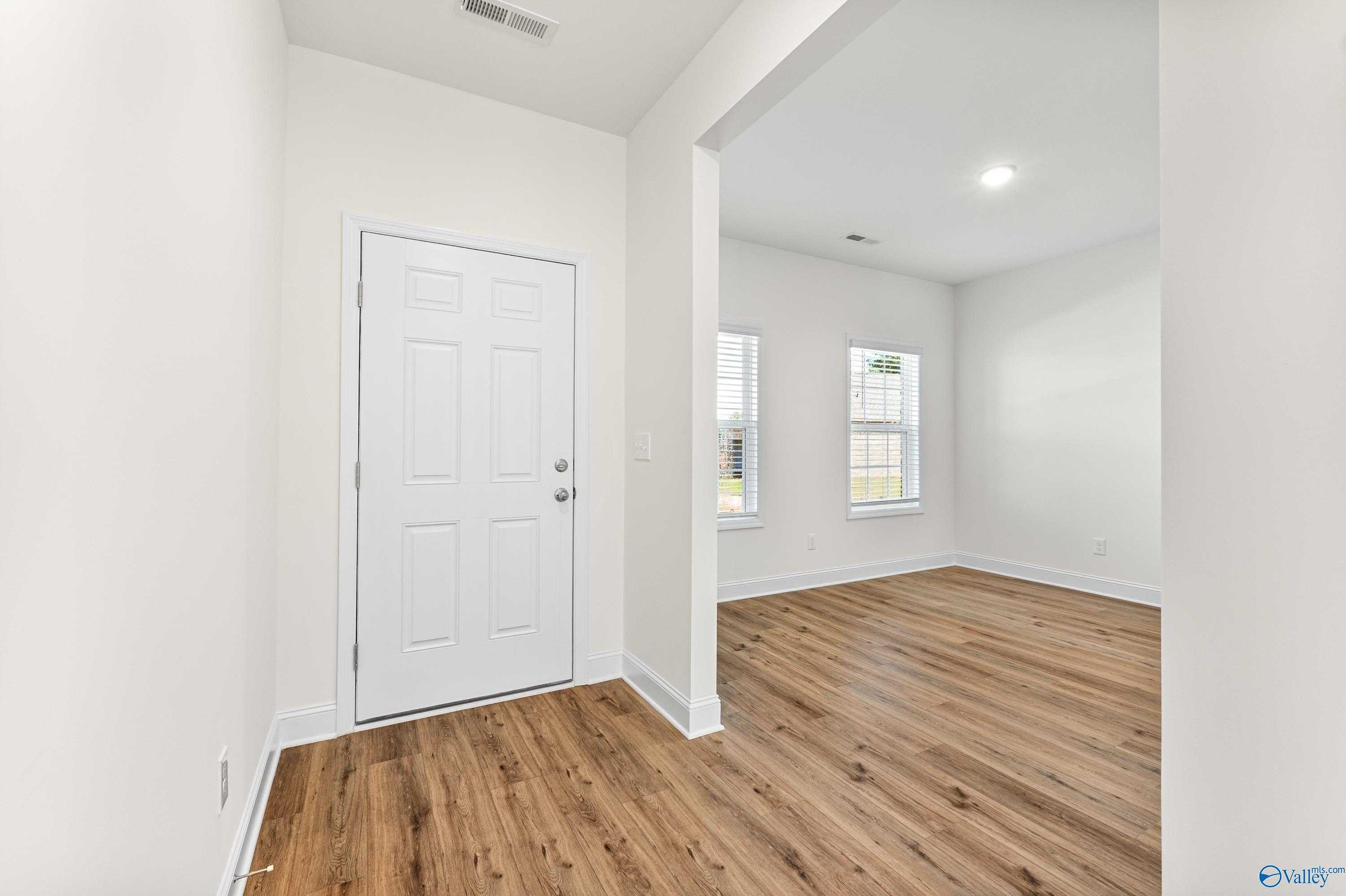 Bright open living space with hardwood floors, white walls, arched entry, and large windows in The Shelby A home, Athens, Alabama