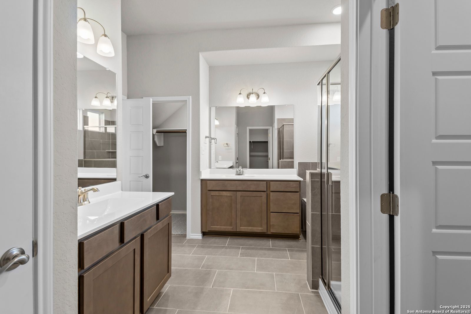 Modern master bathroom featuring double vanity, frameless glass shower, and porcelain tile floor in Davidson Homes The Collin B, Seguin, Texas