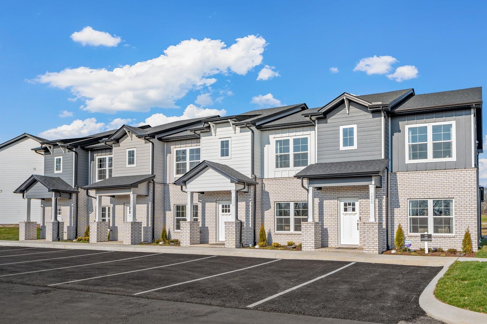 Row of modern 2-story townhomes with gray siding, brick accents, and covered porches in The Towns at Red River, Gallatin, Tennessee