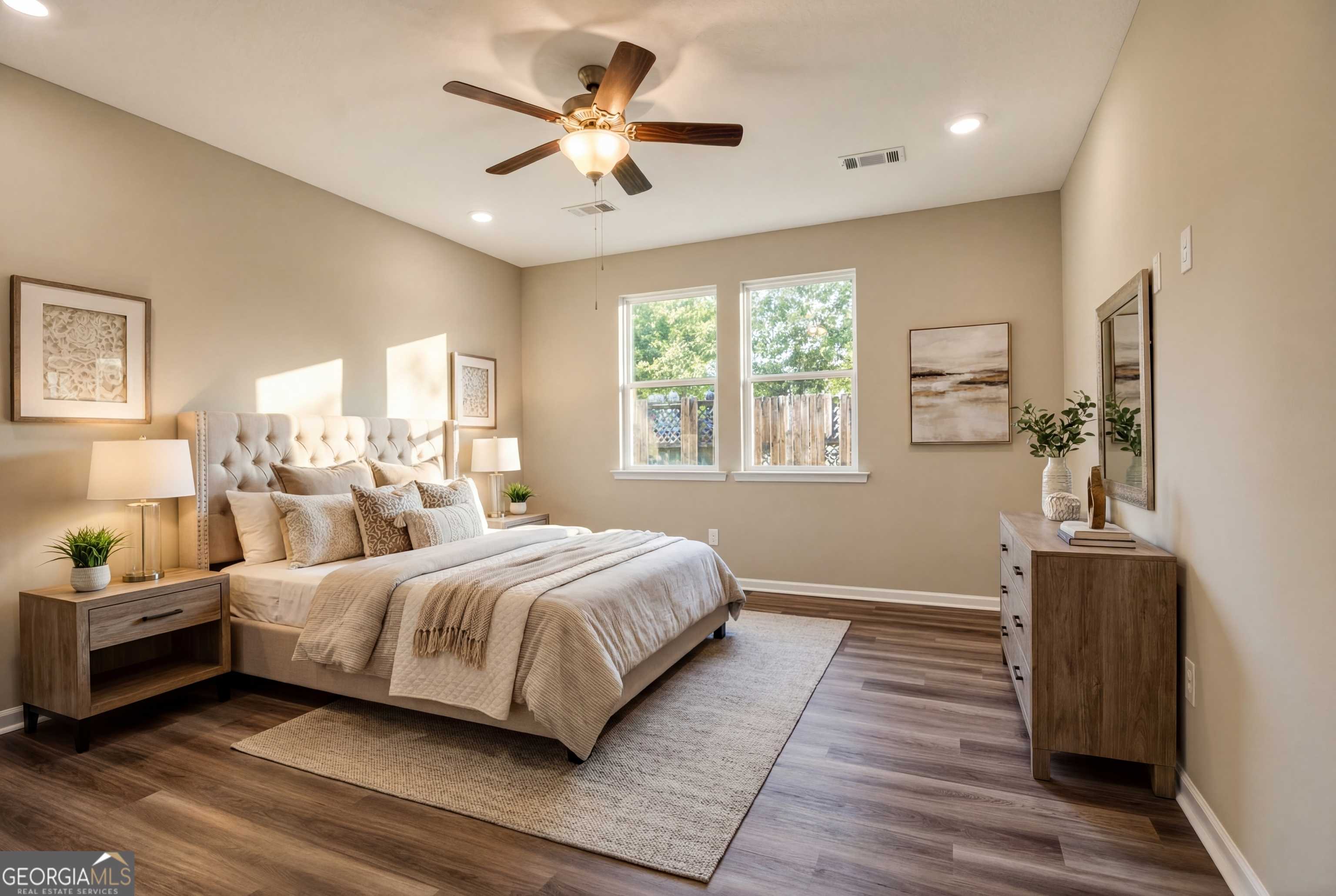 Serene master bedroom with tufted king bed, ceiling fan, and hardwood floors in Evermore Homes The Luna, Ivy Glen, Perry, Georgia