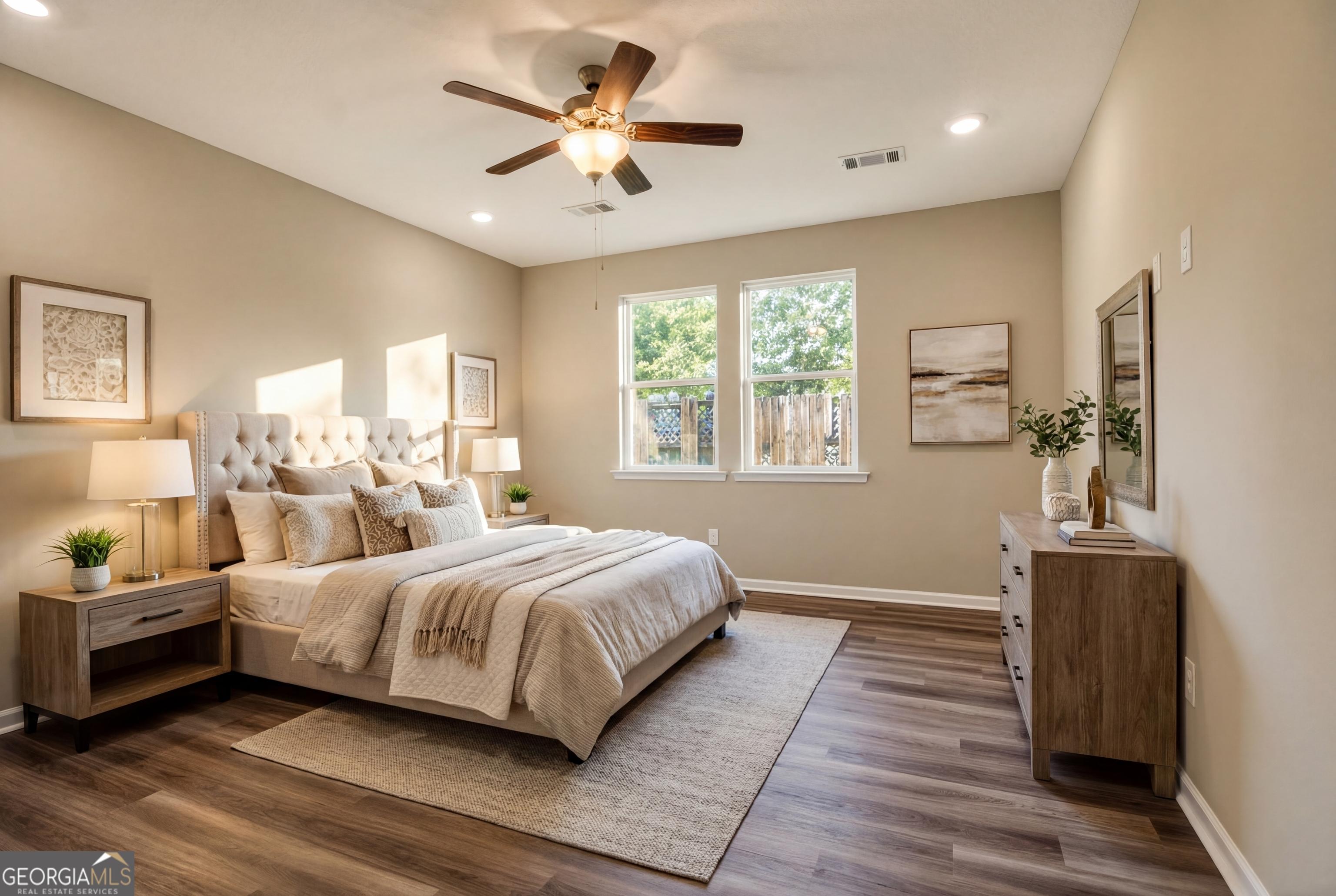 Serene master bedroom with tufted king bed, ceiling fan, and hardwood floors in Evermore Homes The Luna, Ivy Glen, Perry, Georgia