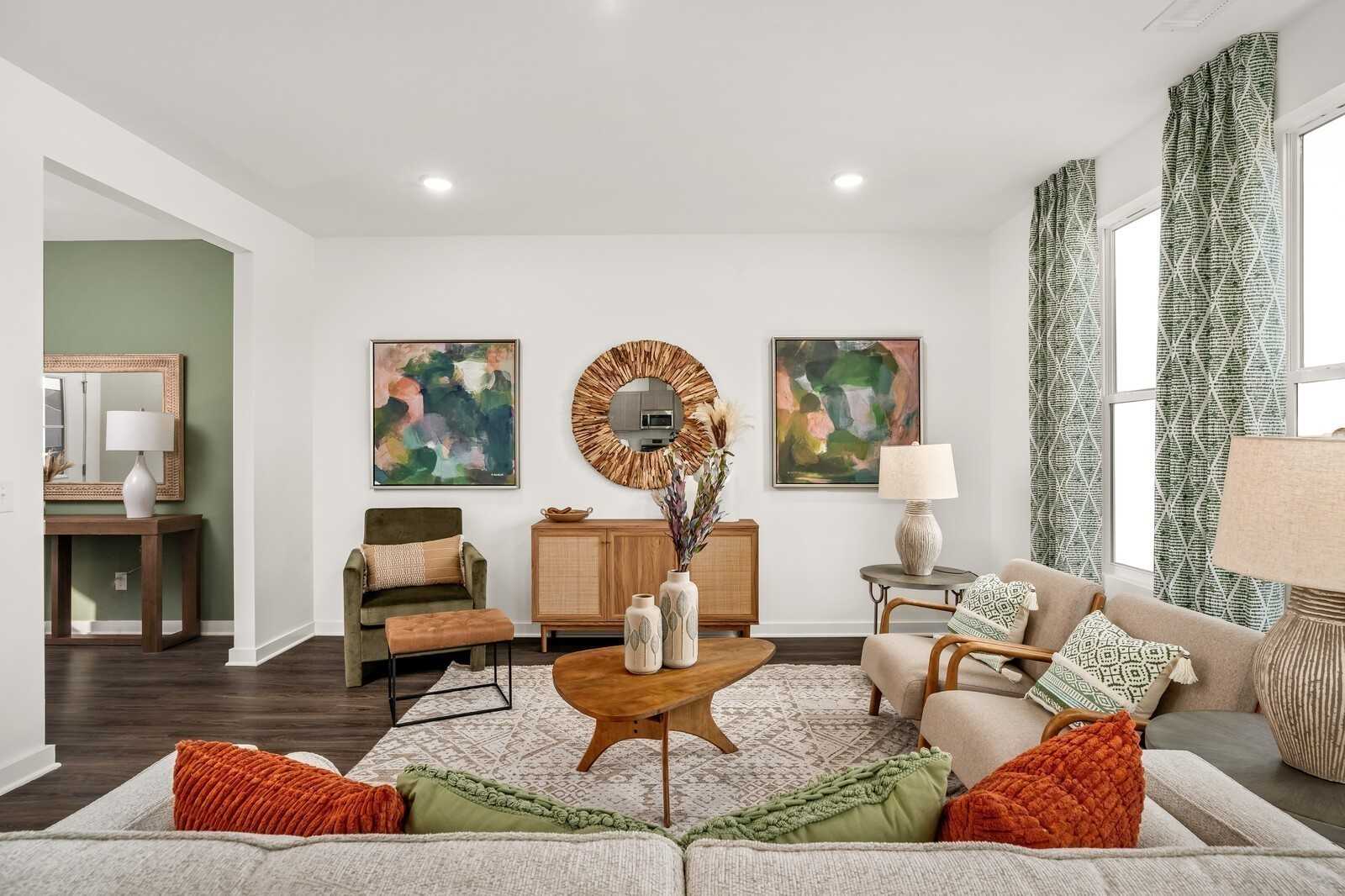 Cozy living room with mid-century wooden furniture, abstract art, green drapes, and large windows in Davidson Homes The Gordon C, White House, TN