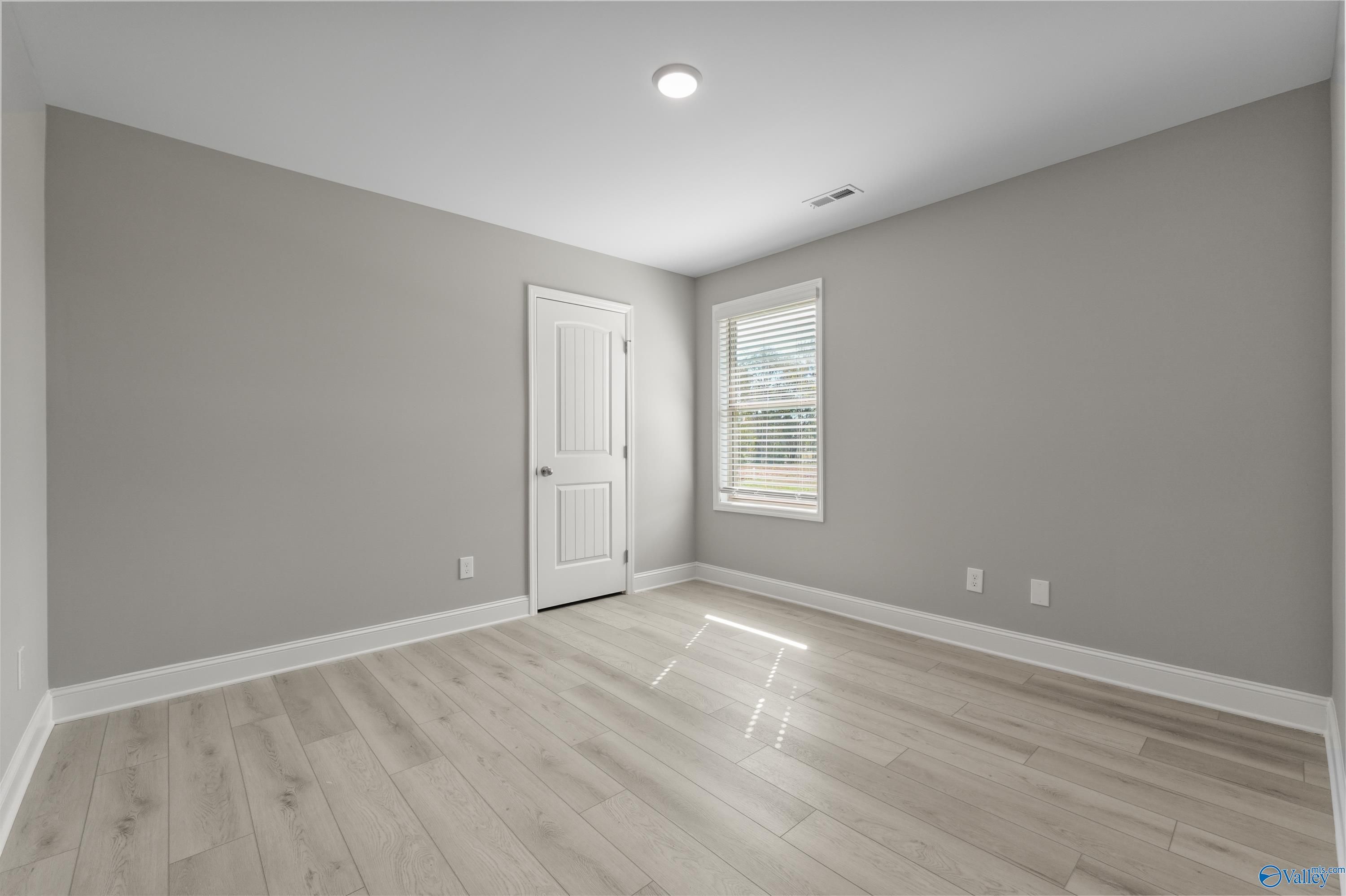 Bright secondary bedroom featuring gray walls, hardwood floors, window blinds in Davidson Homes The Everett B, Athens, Alabama