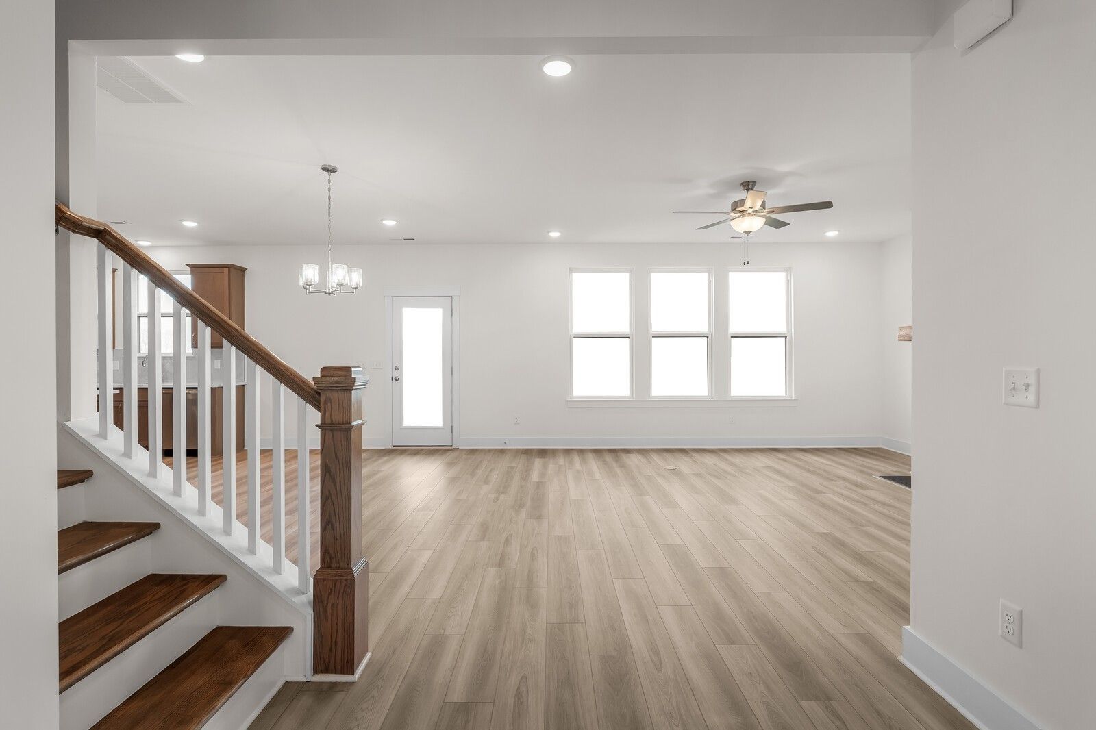 Open-concept living area with wood flooring and staircase in The Henry C floor plan at Benders Cove, Mt. Juliet, Tennessee.