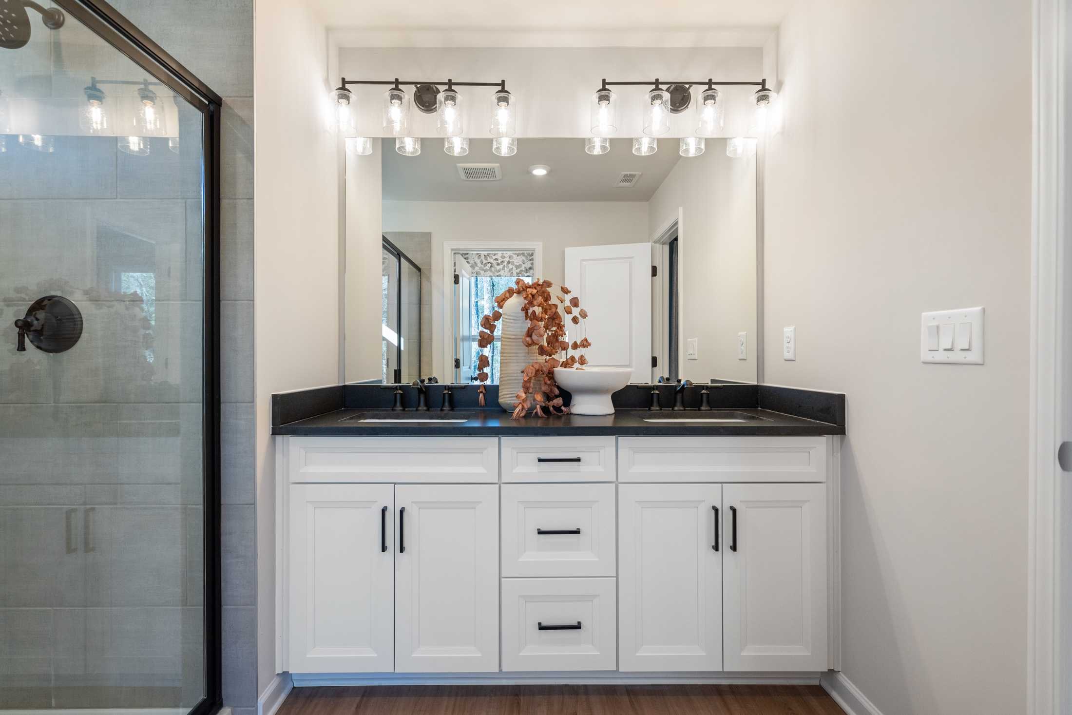 Modern primary bathroom with double vanity, frameless glass shower, and neutral tones at The Village at Shallowford in Kennesaw, GA