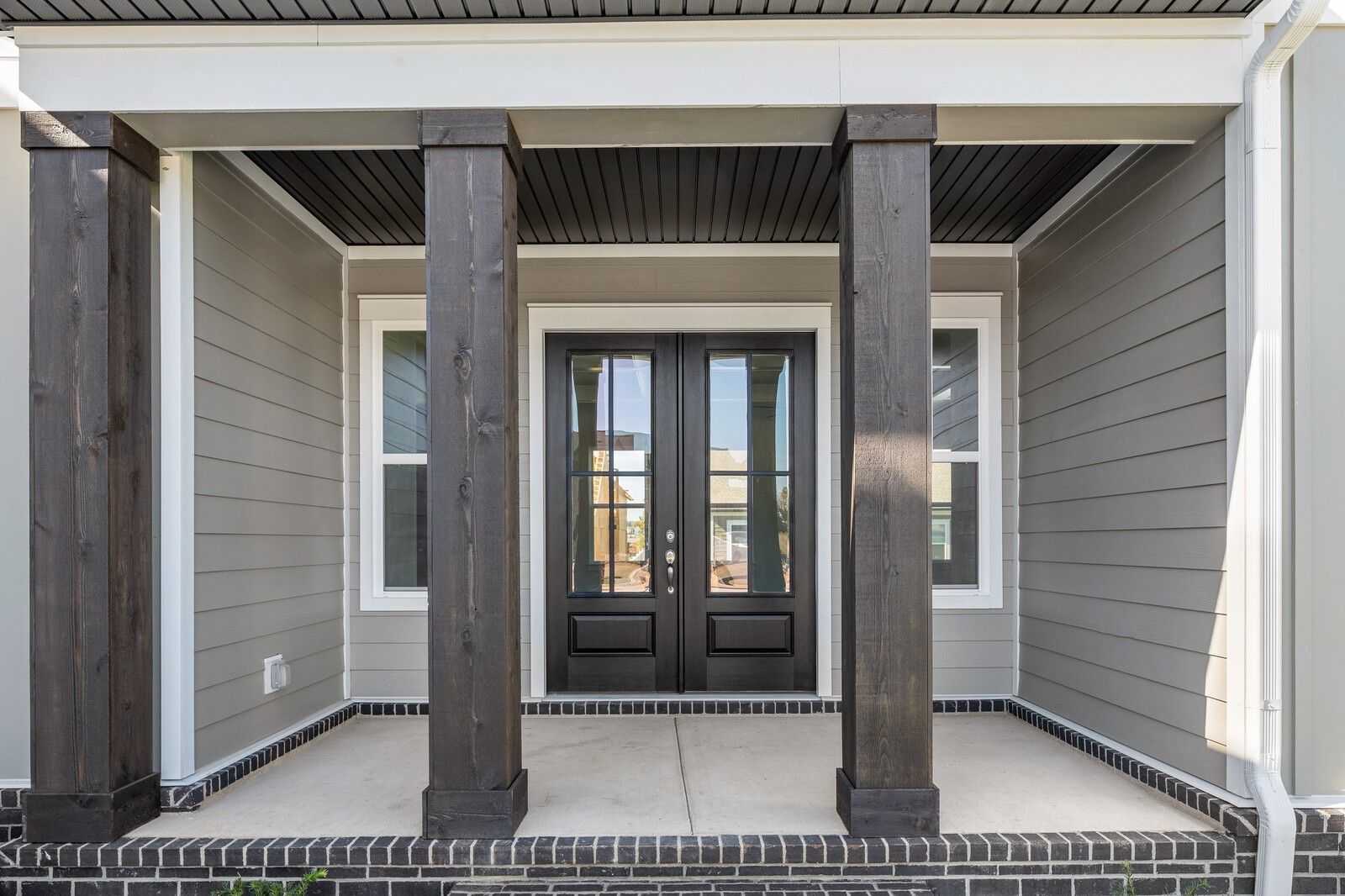 Elegant front porch with double dark wood doors, glass sidelights, and sturdy columns on The Alston A home in Shelton Square, Murfreesboro, Tennessee