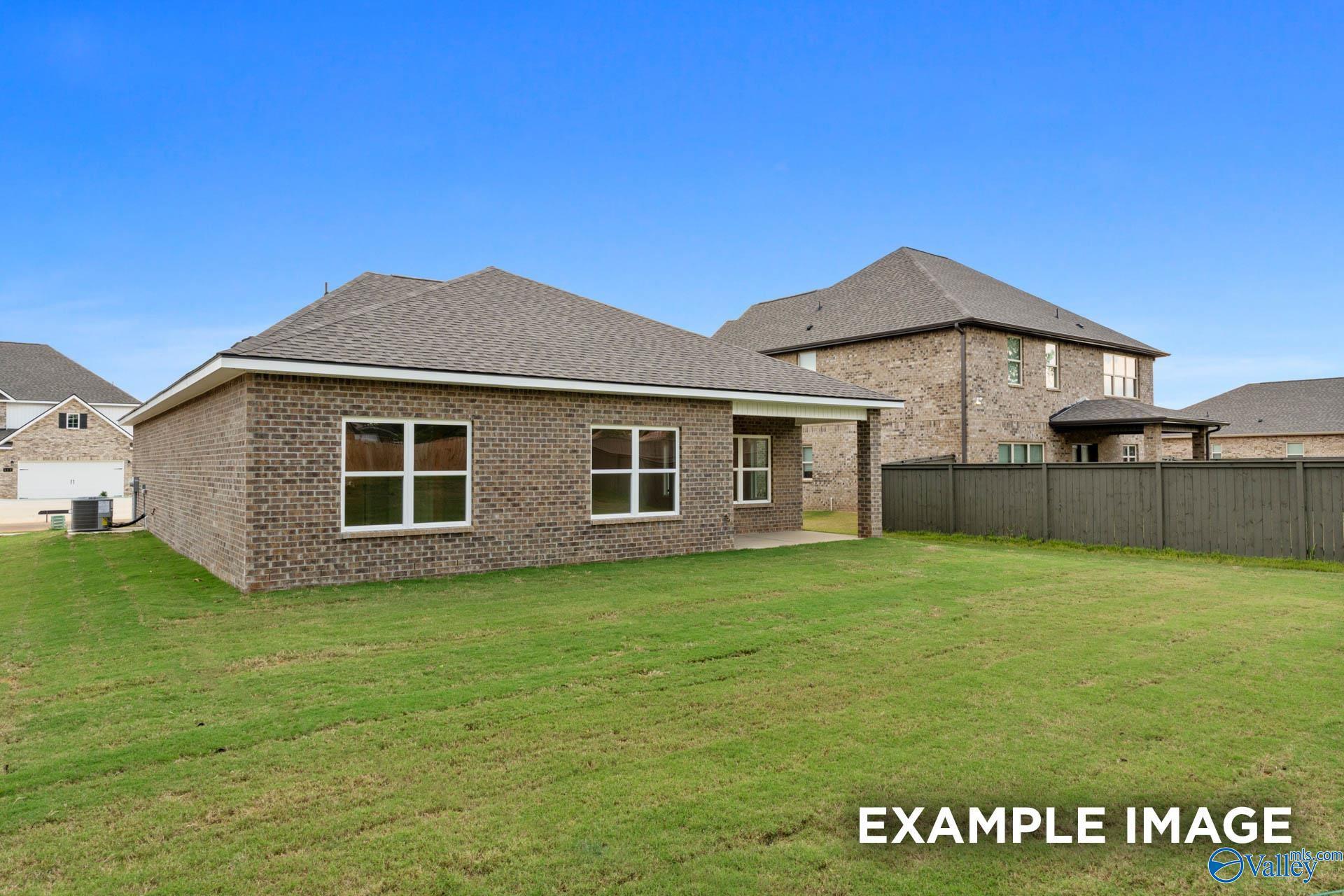 Single-story brick home with 2-car garage, large windows, and fenced green yard in Wood Trail, Toney, Alabama by Davidson Homes