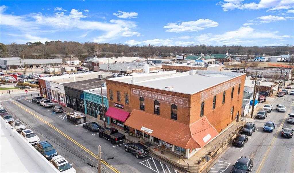 Aerial view of historic downtown Winder, Georgia, featuring Smith Hardware Co. brick building, colorful storefronts, parked cars, and tree-lined streets in Lake Shore area