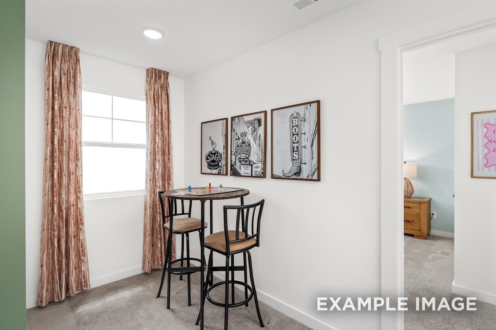 Cozy breakfast nook with round table, black bar stools, and framed art by window in Davidson Homes The Ash A, Gallatin, TN