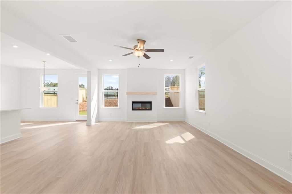 Bright open living room featuring modern fireplace, ceiling fan, and hardwood floors in Davidson Homes The Gavin E, Kennesaw, Georgia