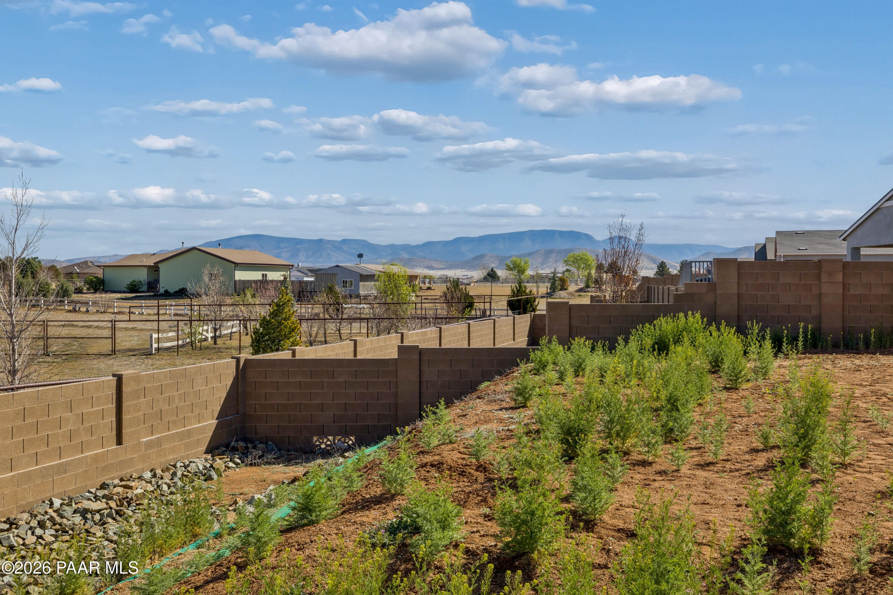 Scenic mountain views beyond block privacy walls and desert shrubs in 3-bedroom Davidson Homes The Harmony A, Prescott Valley, Arizona