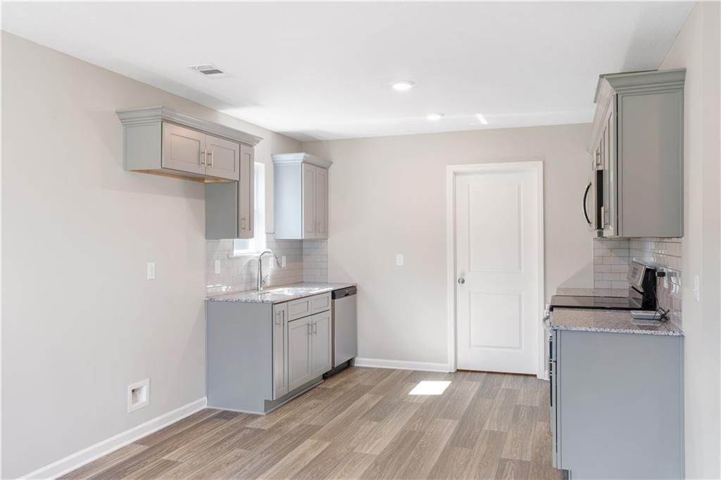 Modern kitchen featuring gray shaker cabinets, granite counters, stainless dishwasher and stove in Davidson Homes The Washington, Phenix City, Alabama