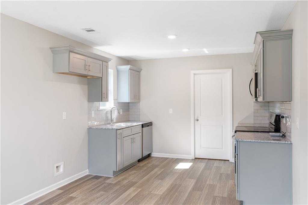 Modern kitchen featuring gray shaker cabinets, granite counters, stainless dishwasher and stove in Davidson Homes The Washington, Phenix City, Alabama