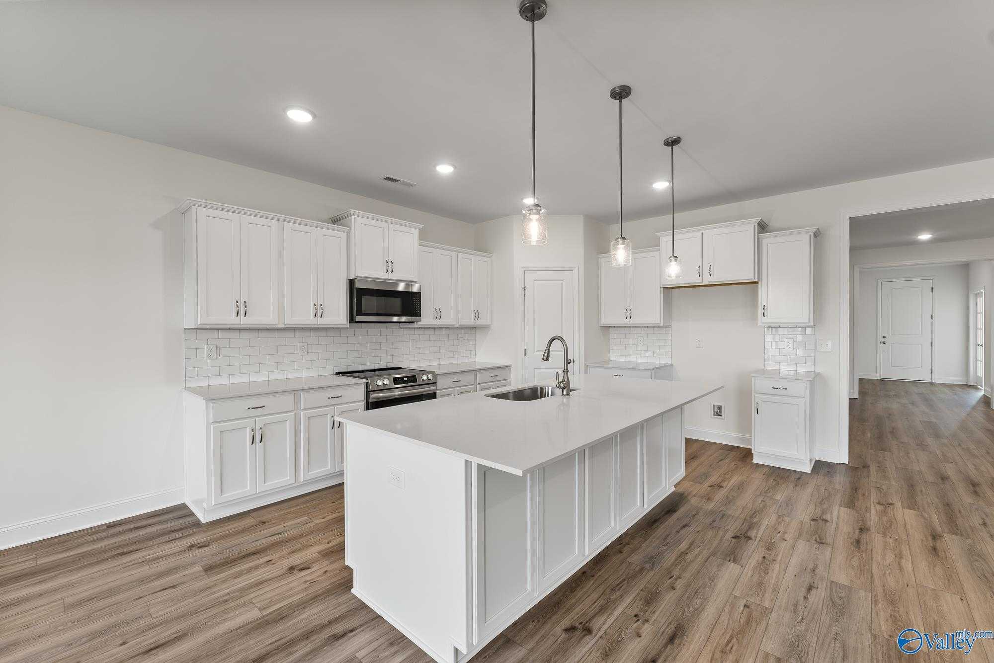 Modern white kitchen with large island, stainless appliances, subway tile backsplash in Davidson Homes The Harrison, Meridianville, Alabama