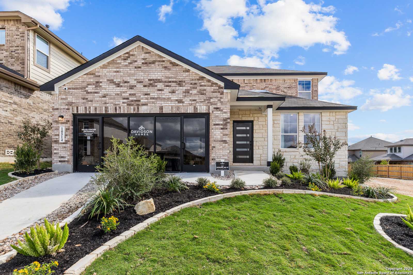 Modern two-story brick home with large front windows, dark entry door, and landscaped front yard in Bricewood, San Antonio, Texas
