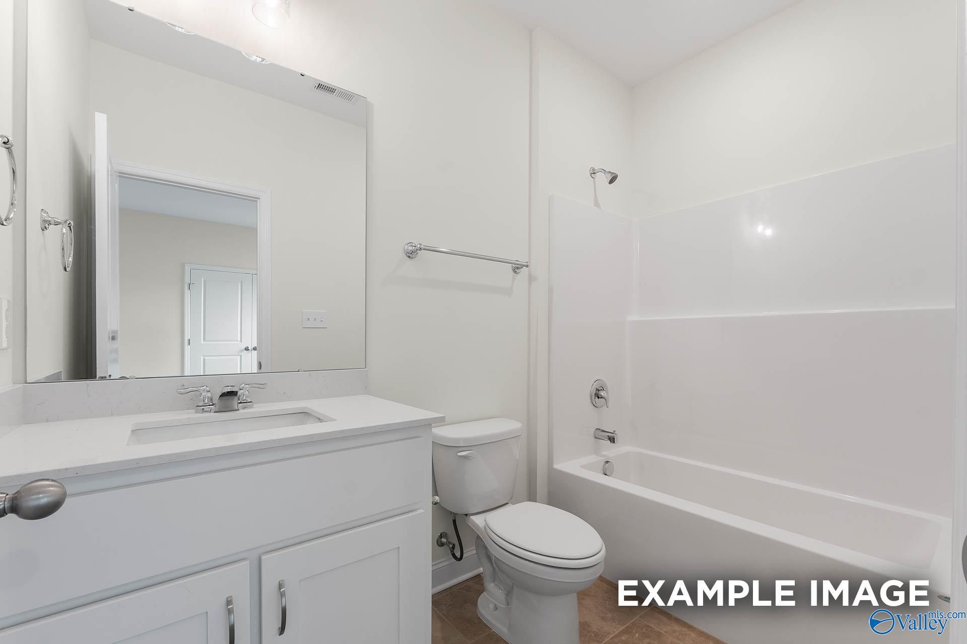 Bright white guest bathroom with tub-shower combo, modern vanity, and mirror in Davidson Homes The Emory, Toney, Alabama