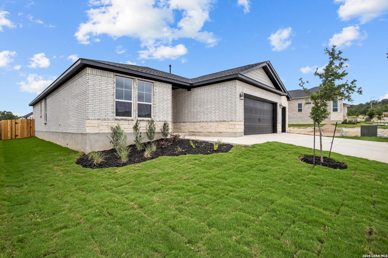 Single-story home exterior with brick facade and two-car garage, The Lanier G floor plan in The Reserve at Potranco Oaks.