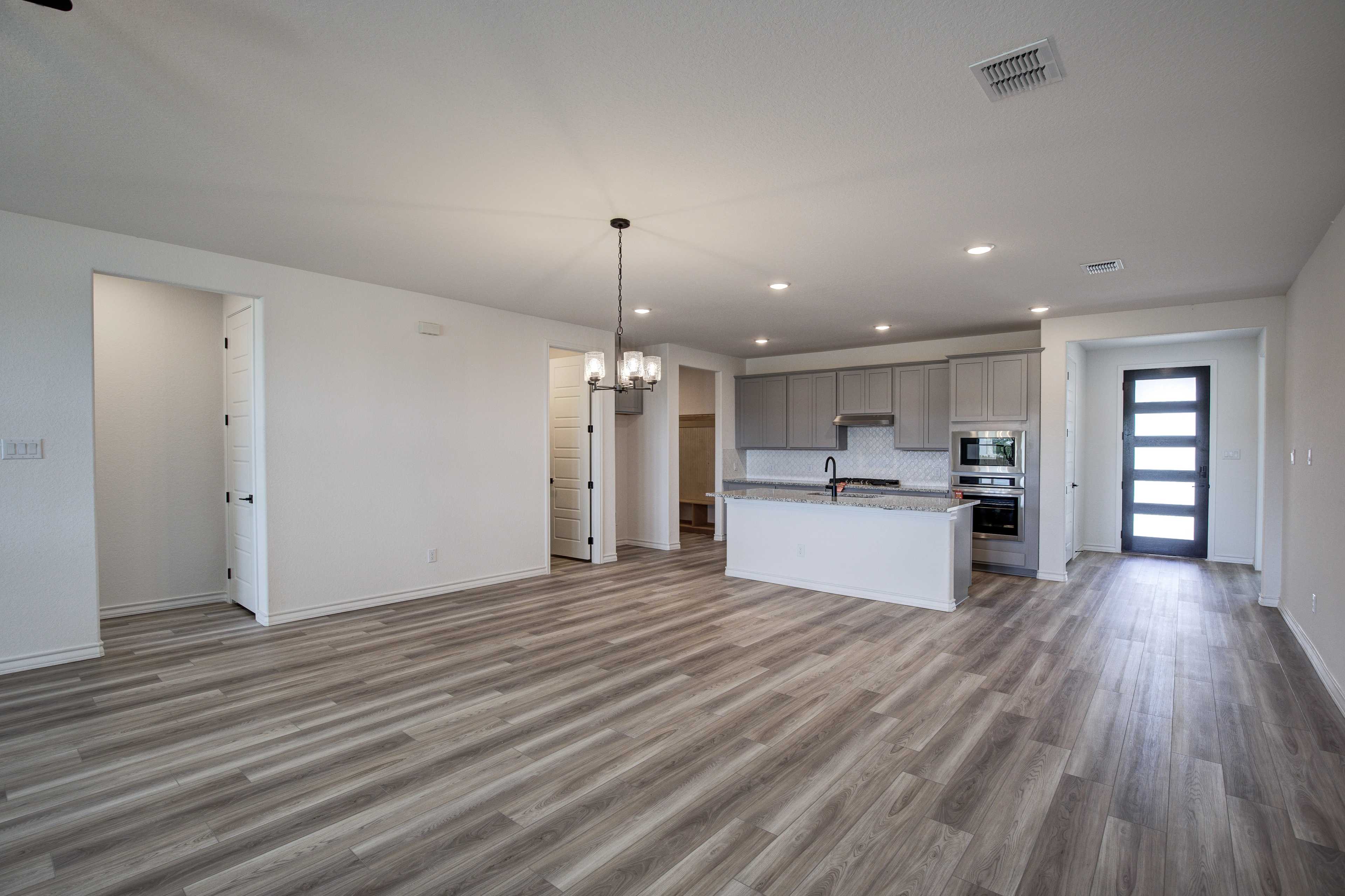 Spacious open-concept kitchen and great room in The Lanier with large white island, gray cabinets, pendant lighting, and luxury vinyl plank flooring